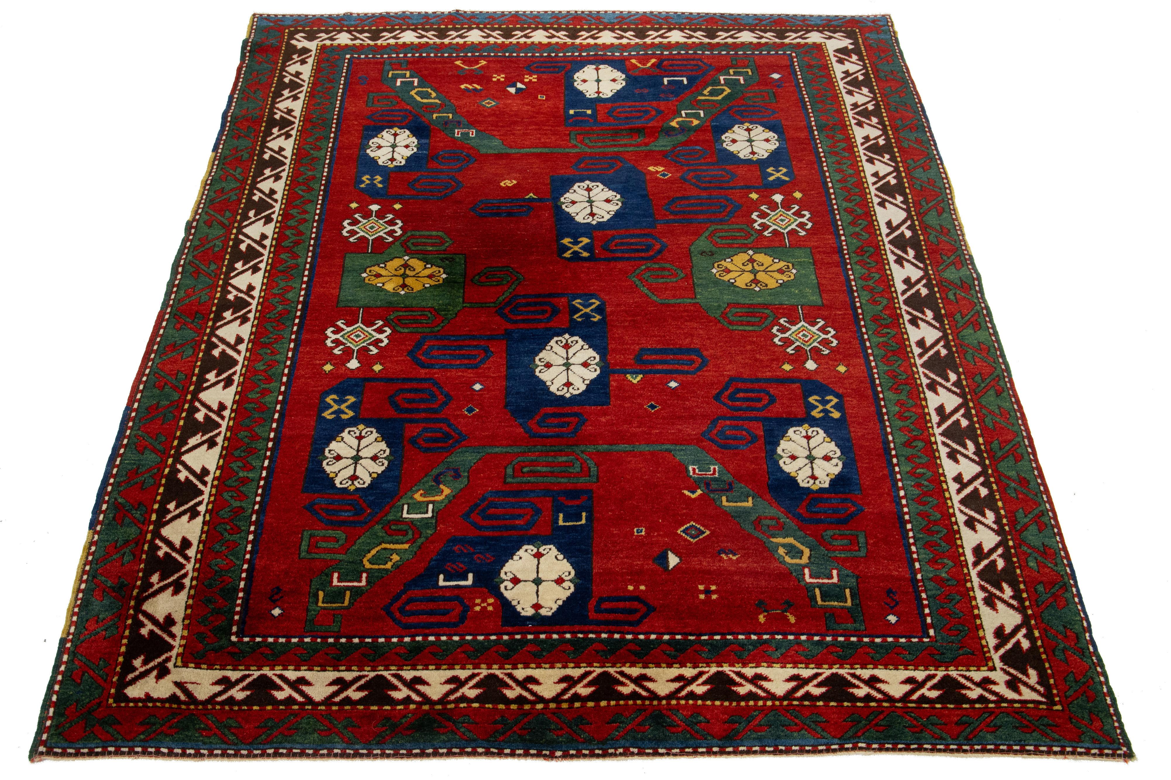 Dieser kasachische Wollteppich wird in sorgfältiger Handarbeit hergestellt. Es ist in einem satten Rot gehalten, das mit zarten Verzierungen in Gelb-, Grün-, Blau- und Beigetönen geschmückt ist. Der Teppich weist außerdem ein kompliziertes