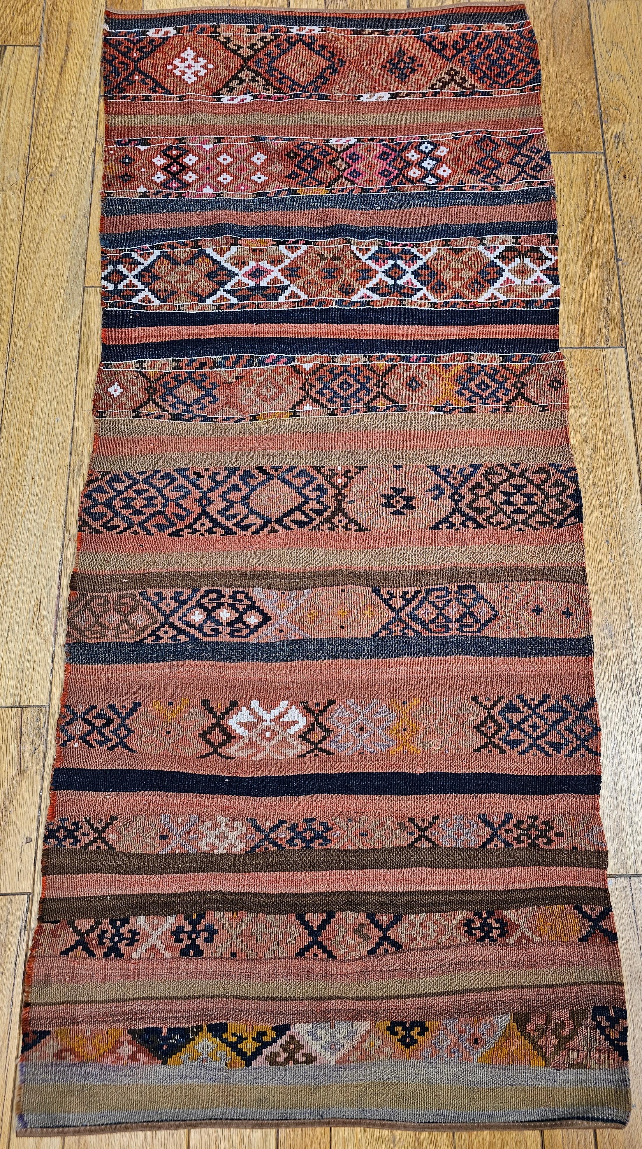 Vintage Caucasian Kilim in an all over stripe design from the early 20th century.  The kilim has traditional hooked star patterns in indigo blue set on a brick red and khaki field.  The designed stripes are  separated by solid bands in dark and