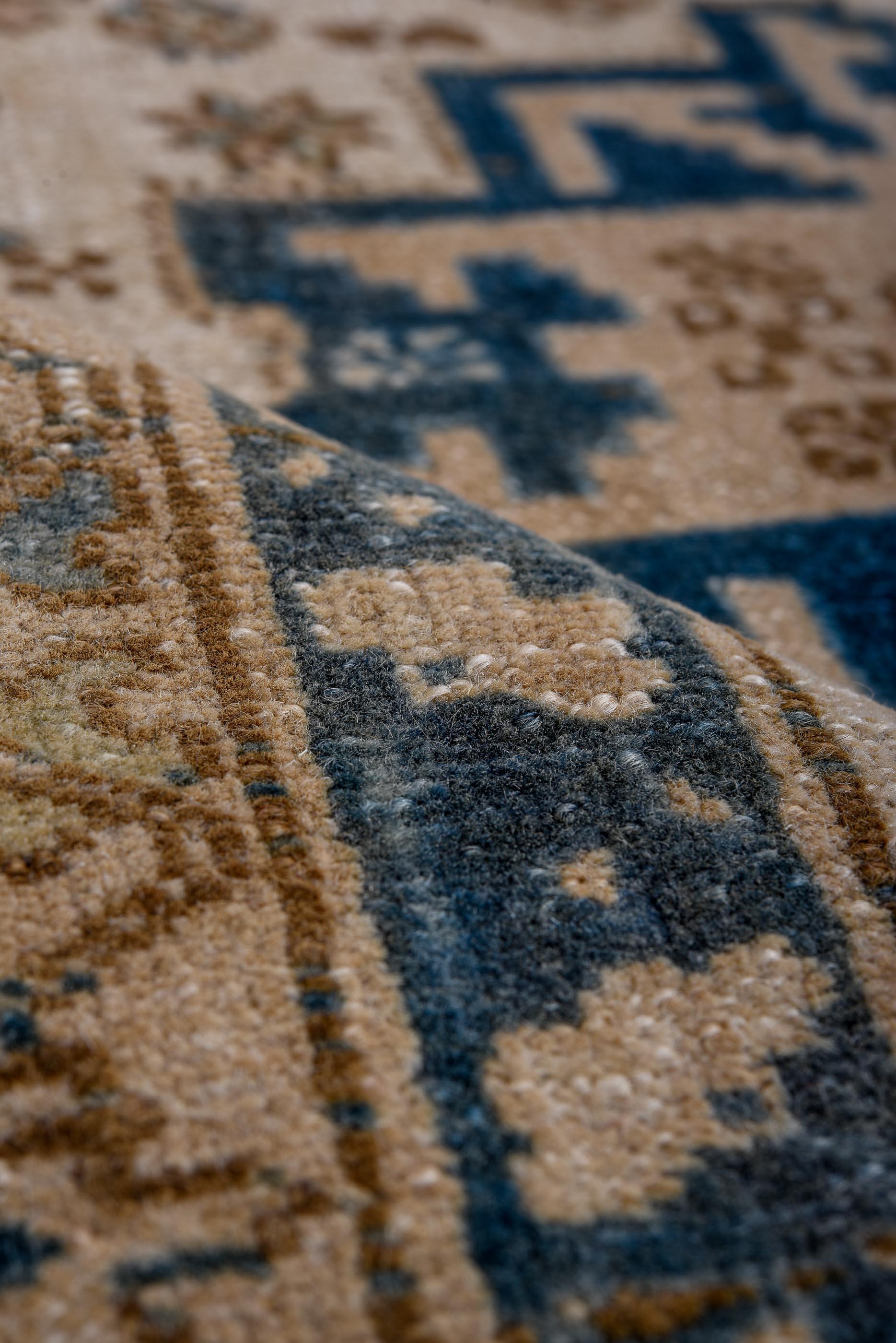 Esta alfombra caucásica vintage presenta un luminoso fondo crema salpicado por una rítmica disposición de medallones escalonados en forma de estrella en azul marino intenso y azul pizarra suave. Acentos de arena, piedra y moca apagado definen los