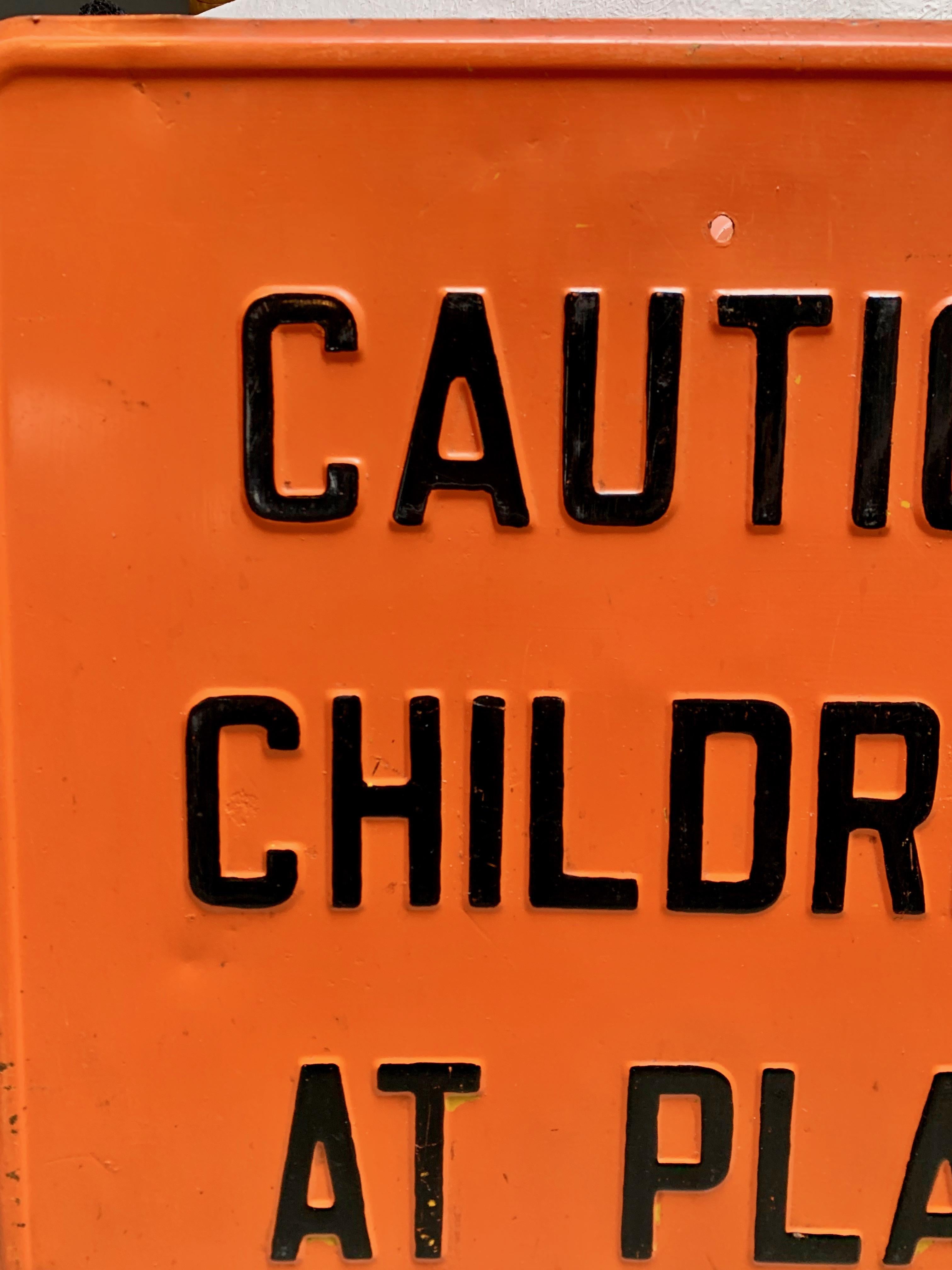 Heavy metal road sign 'CAUTION - CHILDREN AT PLAY.' Orange steel sign with black lettering from the 1970's. Great vintage condition. Fun piece for a kids room or play area.