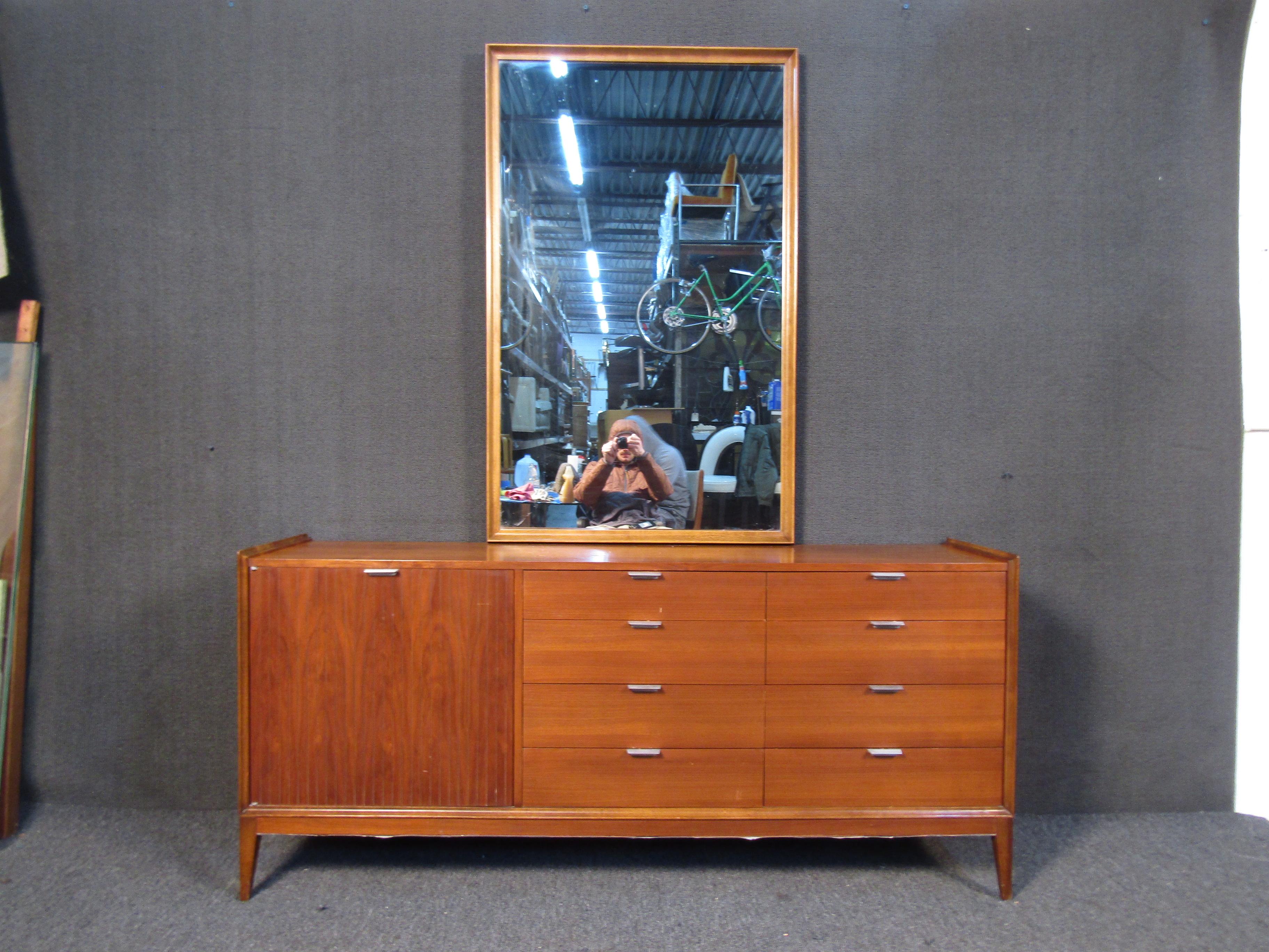 Vintage Cavalier dresser featuring twelve drawers four being behind a door with an elegant metal handle. This dresser also features a mountable mirror in an walnut finish standing at W 34.5 x H 54