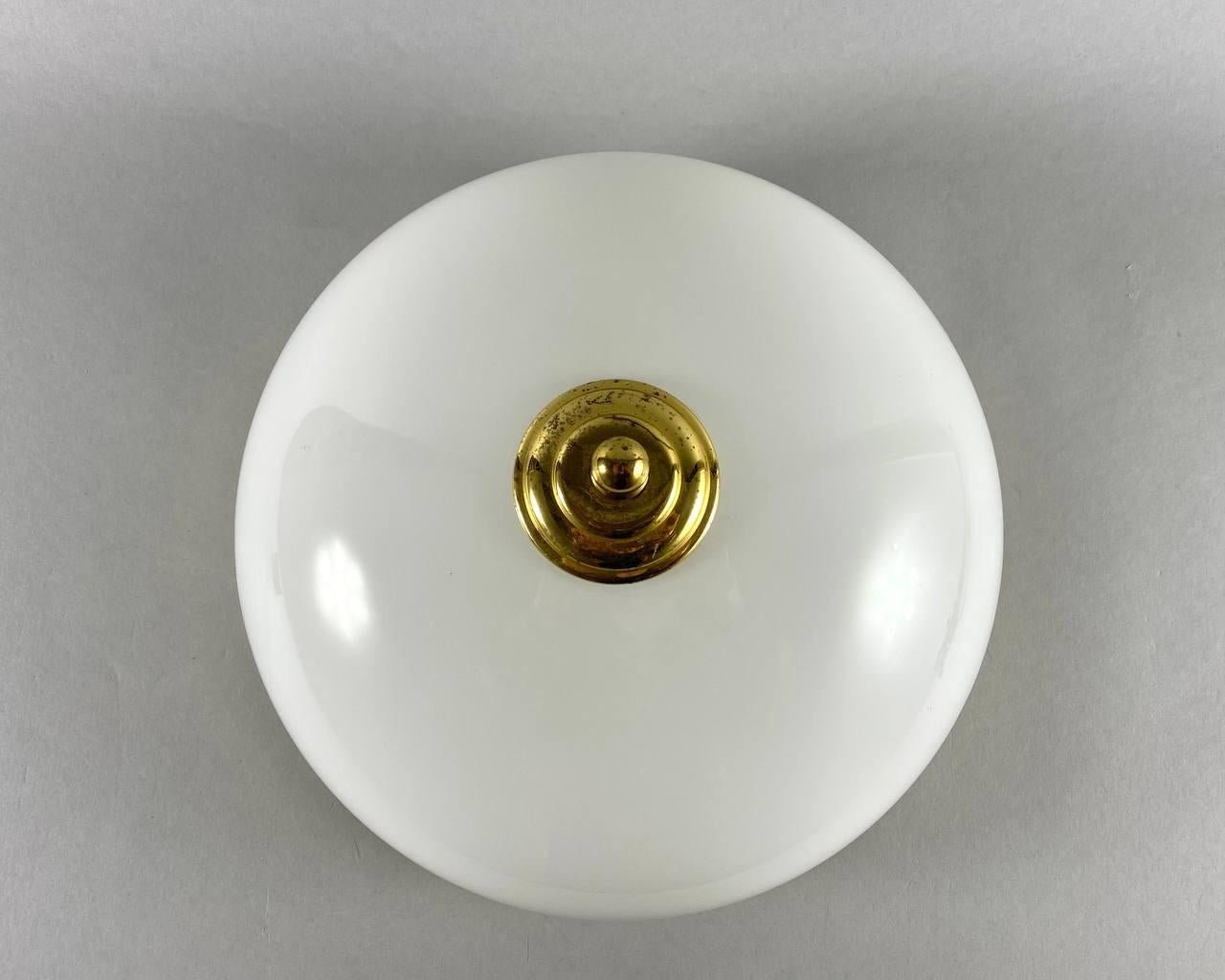 Vintage flush mount ceiling chandelier with 2 light points.

This chic ceiling lamp has a gilt brass fittings, with a shade of amazing white glass, which sparkles beautifully. 

Directly to the ceiling, a round flush-mounted stand. 

Very good