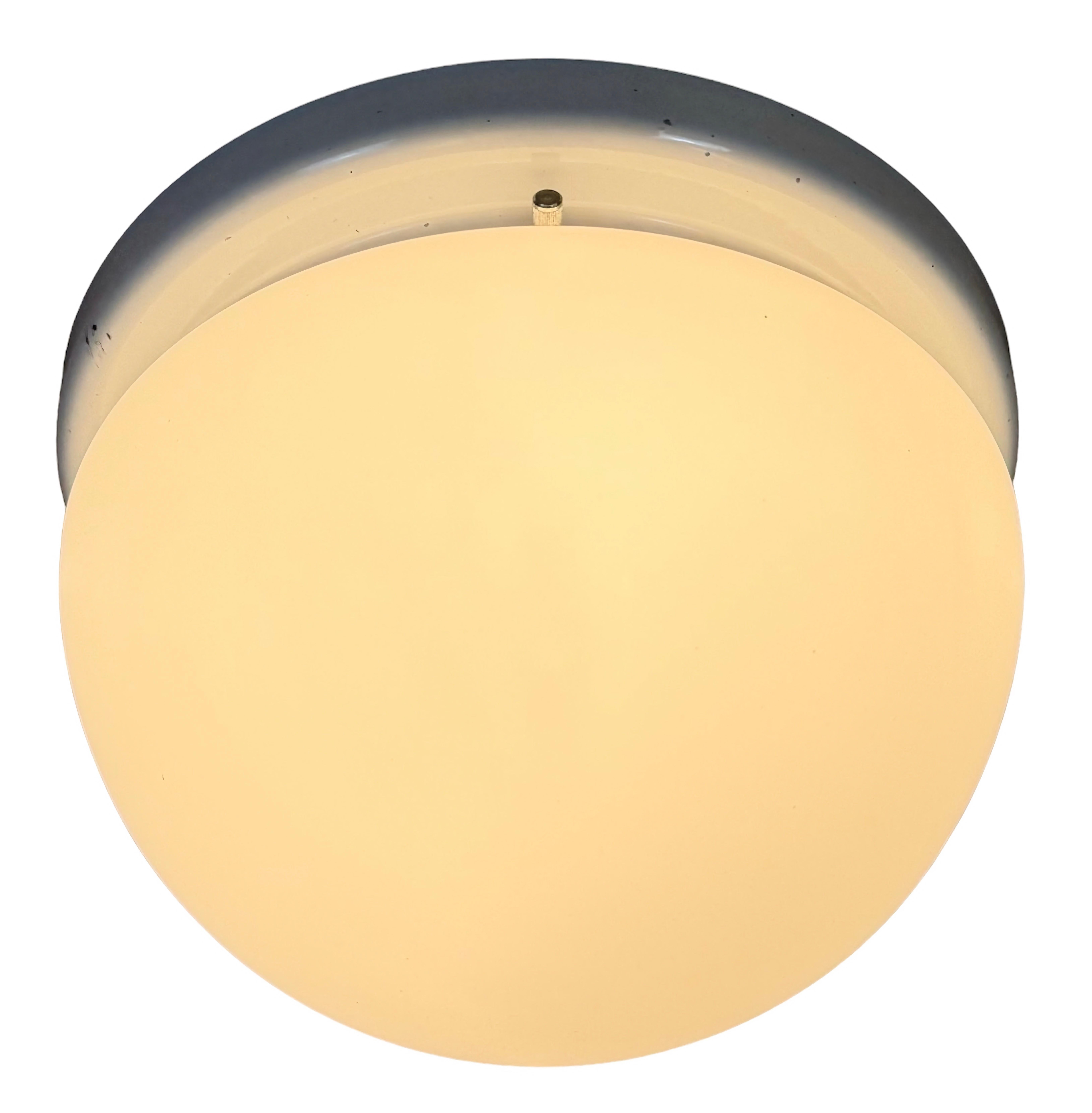 Vintage industrial ceiling or wall light  made in former Czechoslovakia during the 1980s.It features a white iron wall or ceiling mounting and a milk glass cover. The socket requires standard E27/E 26 light bulbs. New wire. 
The weight of the lamp