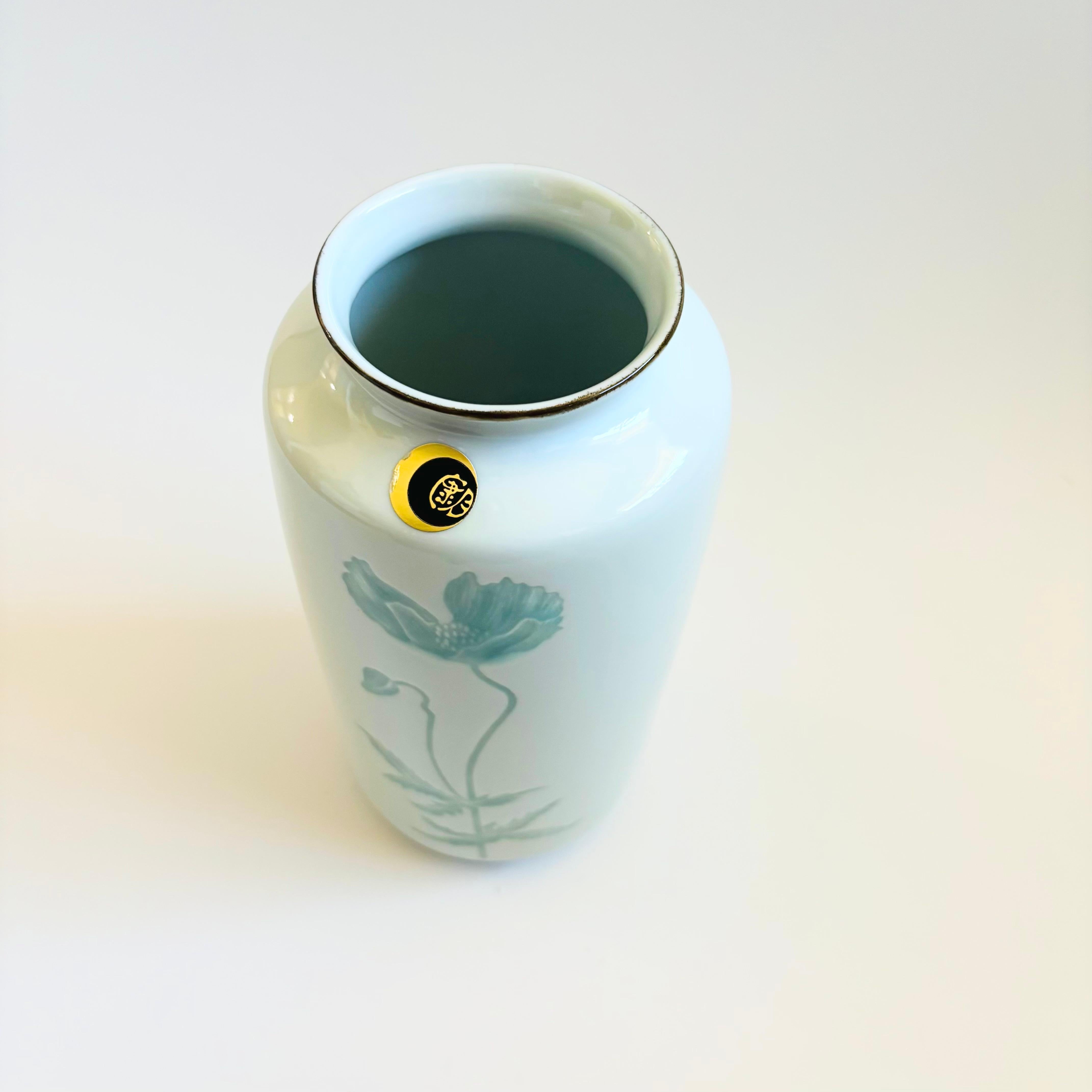 Un vaso vintage in ceramica giapponese con un grazioso disegno di papaveri. Una forma semplice e piacevole con una finitura verde celeste lucida. Adesivo originale allegato.

