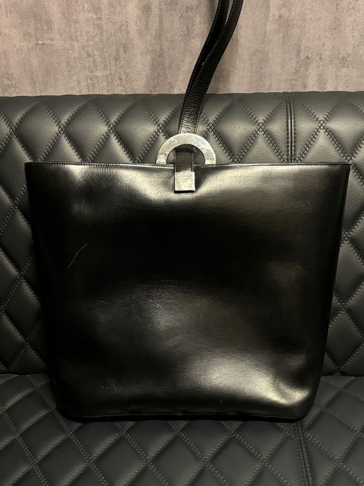 Sac seau Vintage Celine en cuir noir avec boucle. Taille assez grande, convient très bien. Design/One intéressant. Livré en l'état. Présente des éraflures et des rayures sur toute la surface du cuir, avec des plis mineurs sur la sangle.