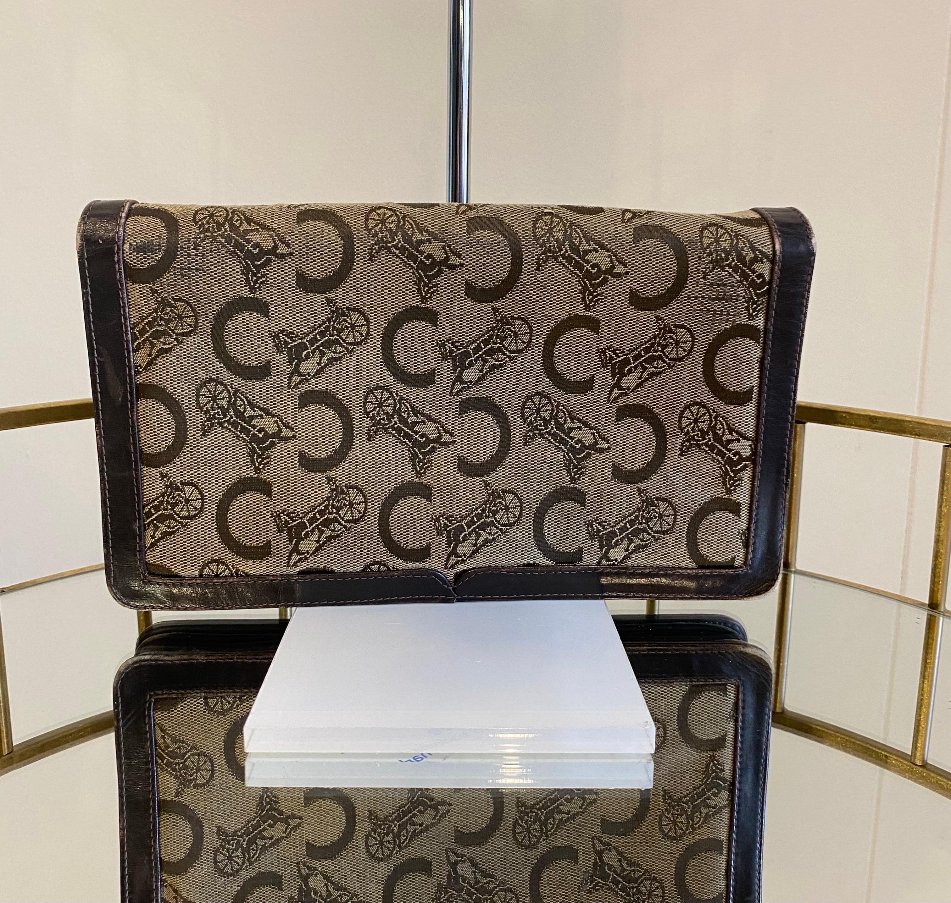 Vintage Céline clutch bag in patterned fabric and brown leather. On the front golden hardware engraved with the logo. The interior is made up of three compartments, two of which have zip closures. It shows signs of normal use especially on the