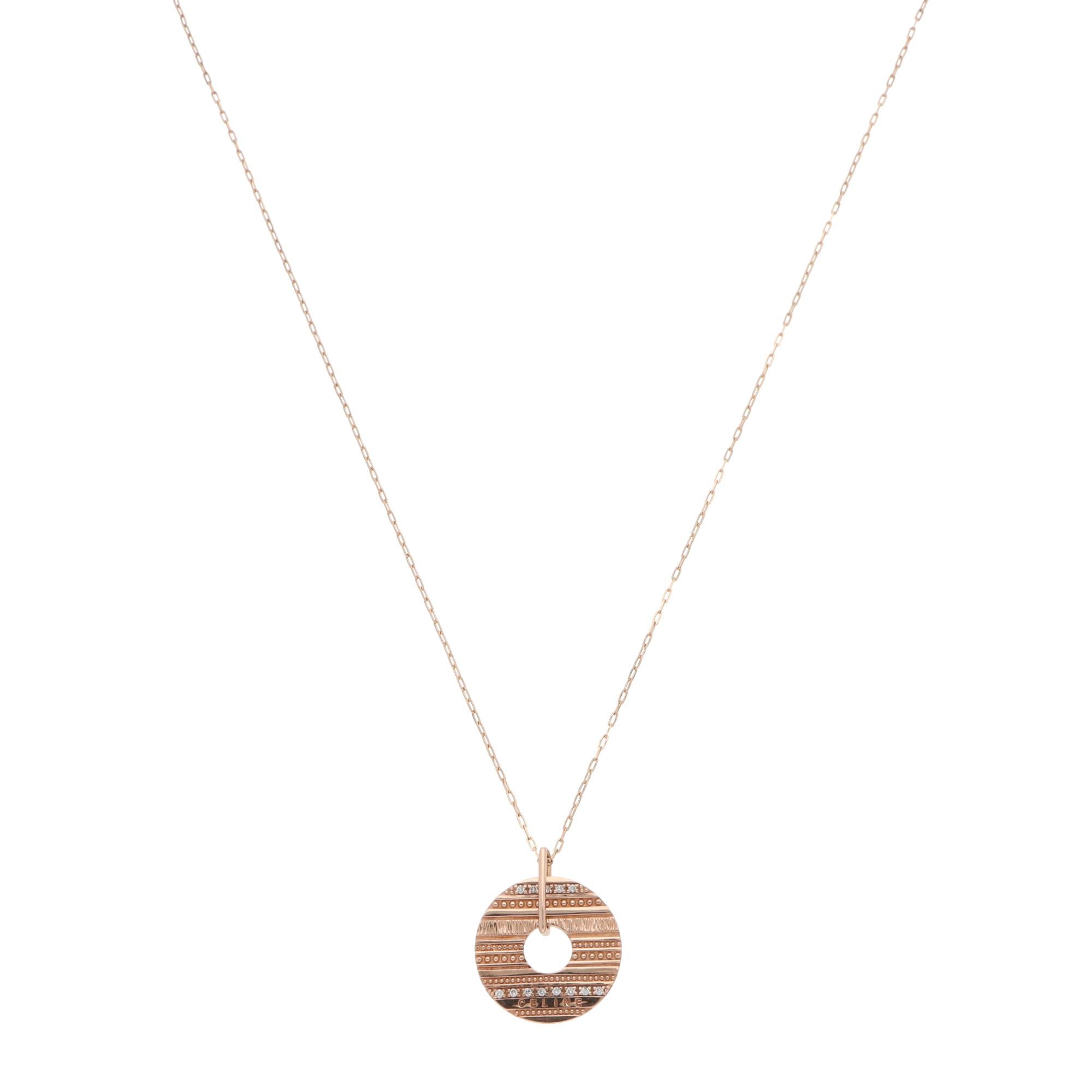 Precioso collar vintage Celine con colgante de disco circular engastado en oro rosa macizo de 10 quilates.

El colgante se compone de un disco macizo de oro rosa pulido perforado centralmente con una abertura circular. El disco está engastado con 13