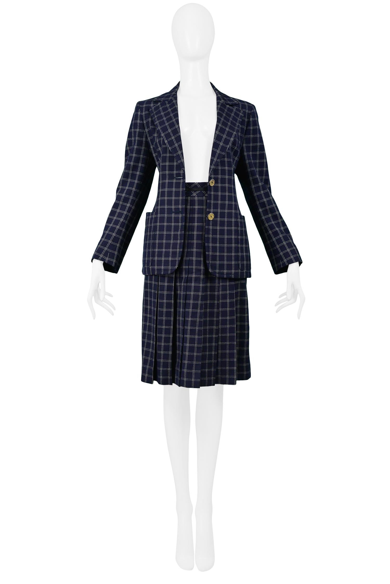 Vintage Céline wool skirt suit with navy and white windowpane plaid. The ensemble features a skirt with box pleats, gold tone and leather belted detail at waist and a jacket with a double button front closure and pockets at the side. Circa