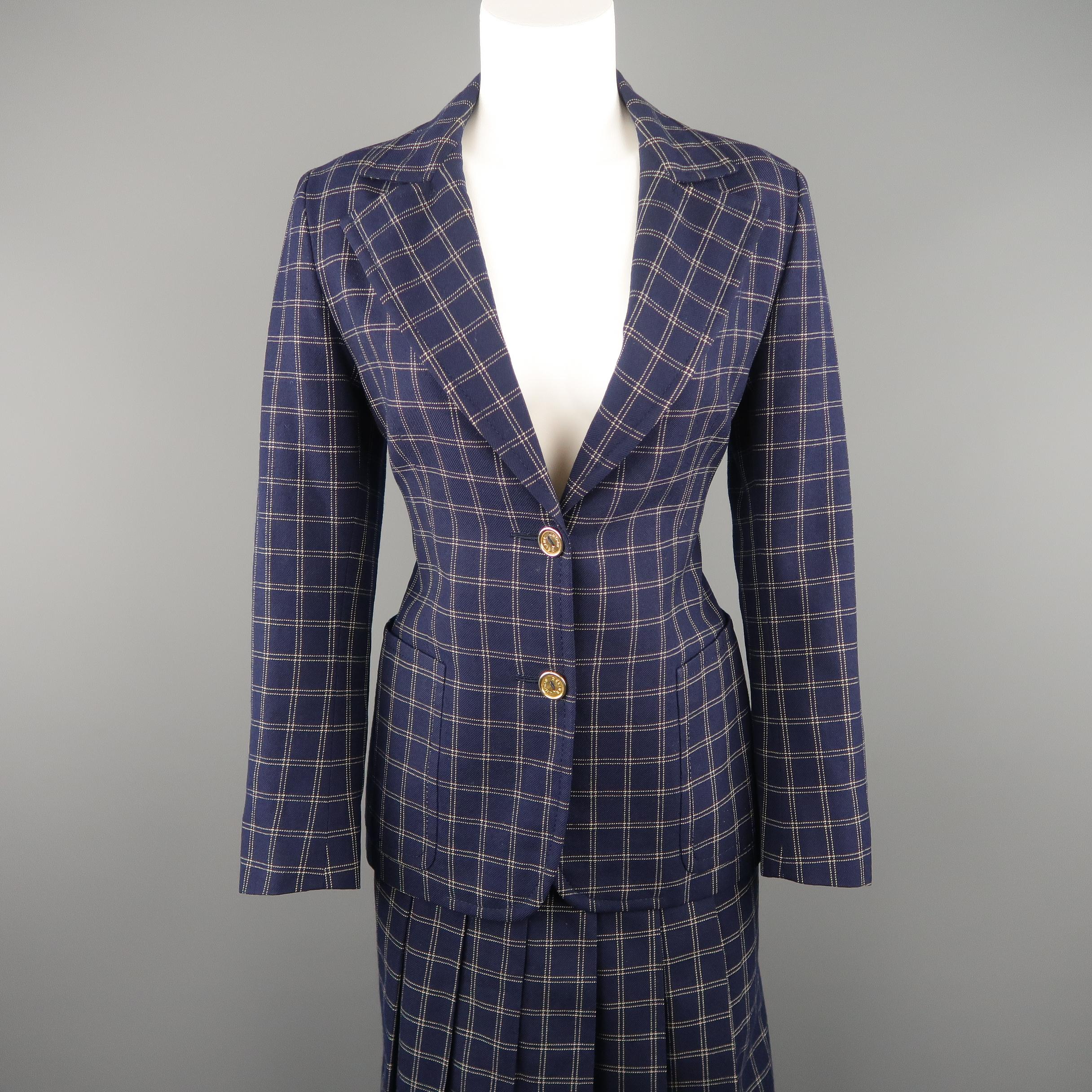 This rare vintage CELINE suit comes in navy and white windowpane grid print wool twill and includes a single breasted blazer with 2 gold tone logo button frontal closure, notch lapel, and patch pockets with a matching box pleated skirt accented with