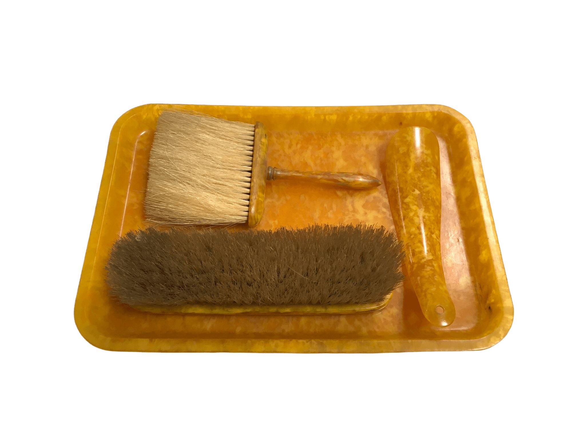 Vintage Celluloid Vanity Set with Tray, Clothing Brush, Hat Brush, and Shoe Horn.
 
Every single piece in this set is in great condition. Made out of bakelite, it features a nice marbled yellow-orange pattern. Slight signs of use, but no dents,