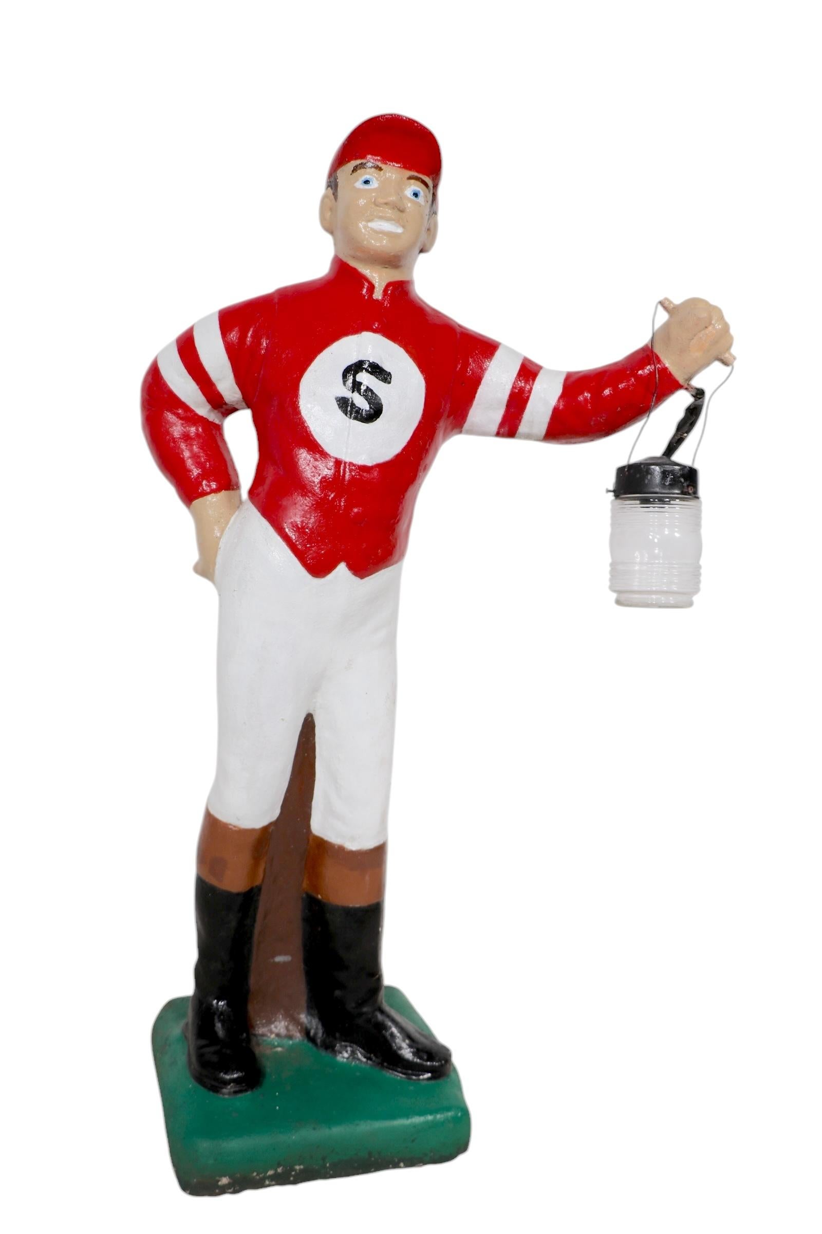 Classic poured stone lawn jockey, from an estate in Saratoga NY. The jockey is in hand painted finish, with a large bold S on his chest. This example is in very good, ready to display condition, with a functional electrified lantern. 
