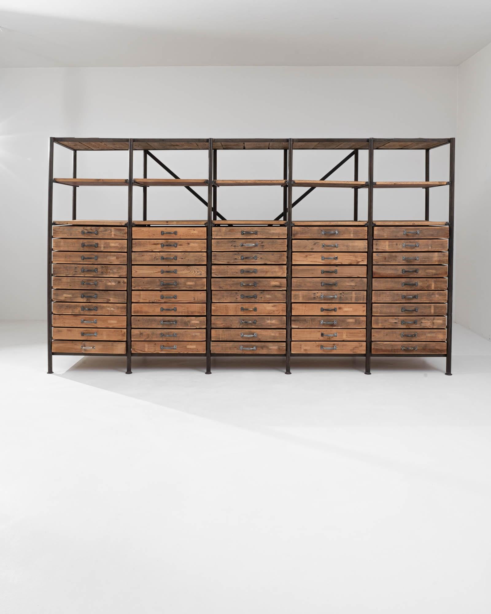 A wooden and metal shelving unit created in 20th century Central Europe. Five columns of ten drawers each stretch across the expansive composition of this delightful shelving unit. Weathered wood slotted into a welded steel frame creates a