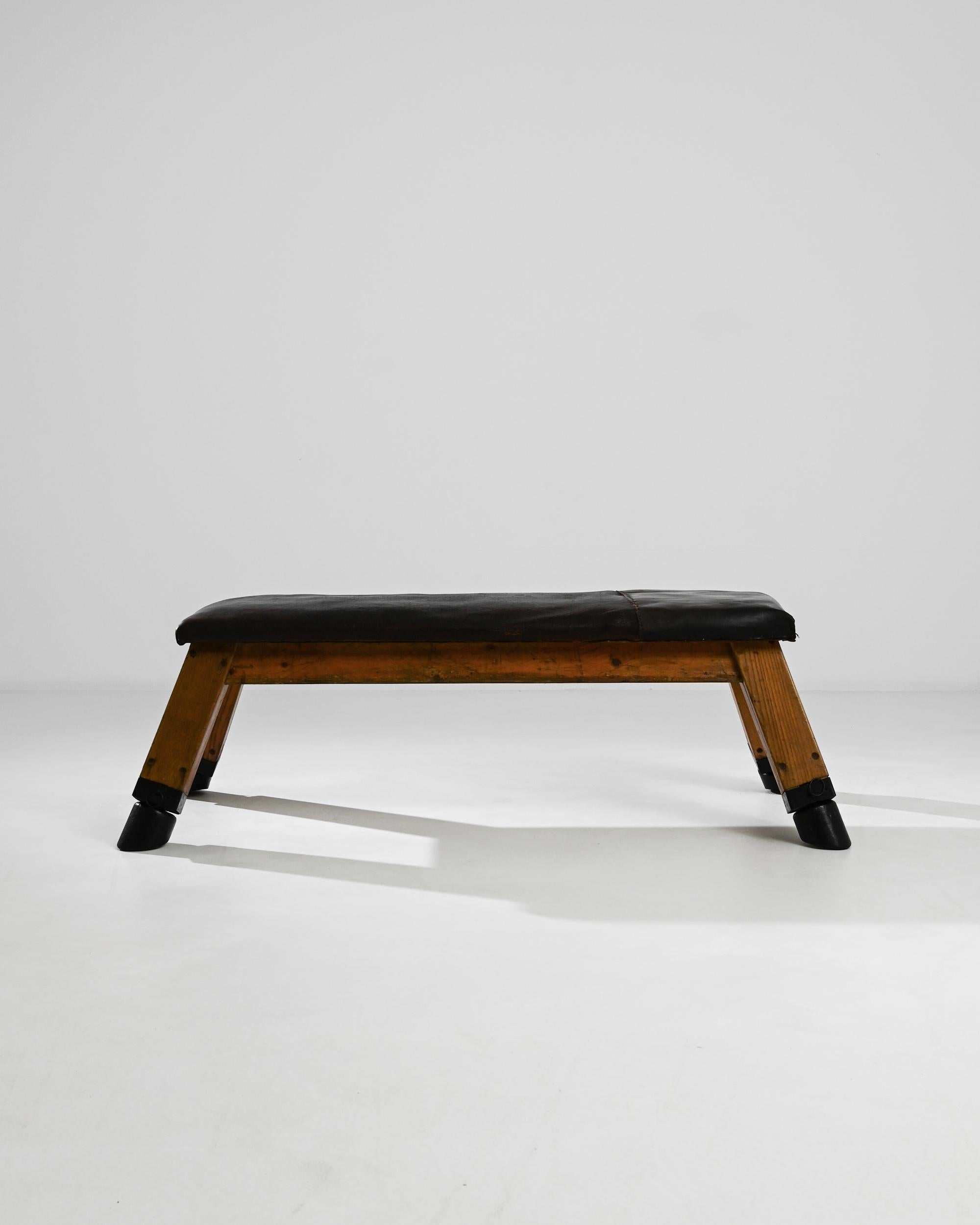 This leather pommel horse was made in the former Czechoslovakia, circa 1950. Originally used by gymnasts for swinging and balancing exercises, this pommel horse features a low seat, supported on four splayed legs. With a rich patina weathered by the