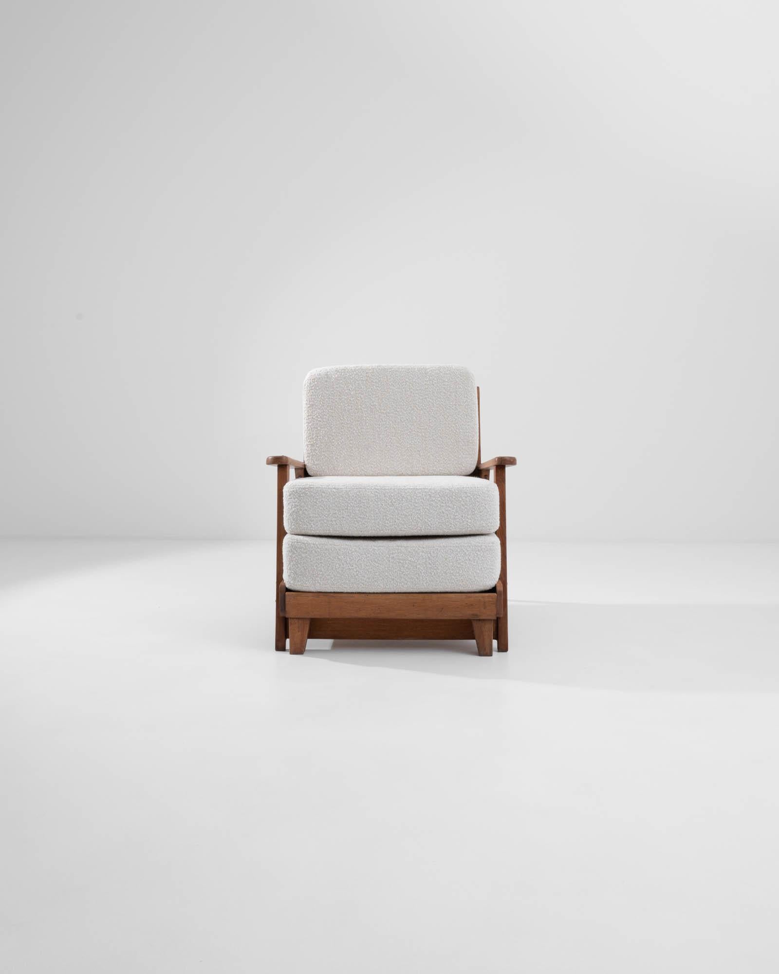 A 20th century wooden upholstered armchair created in 20th century central Europe. In classic mid-century central European style, this fascinating armchair blends a chic minimalism with a warm and cozy appeal. A charming feat of design, this chair