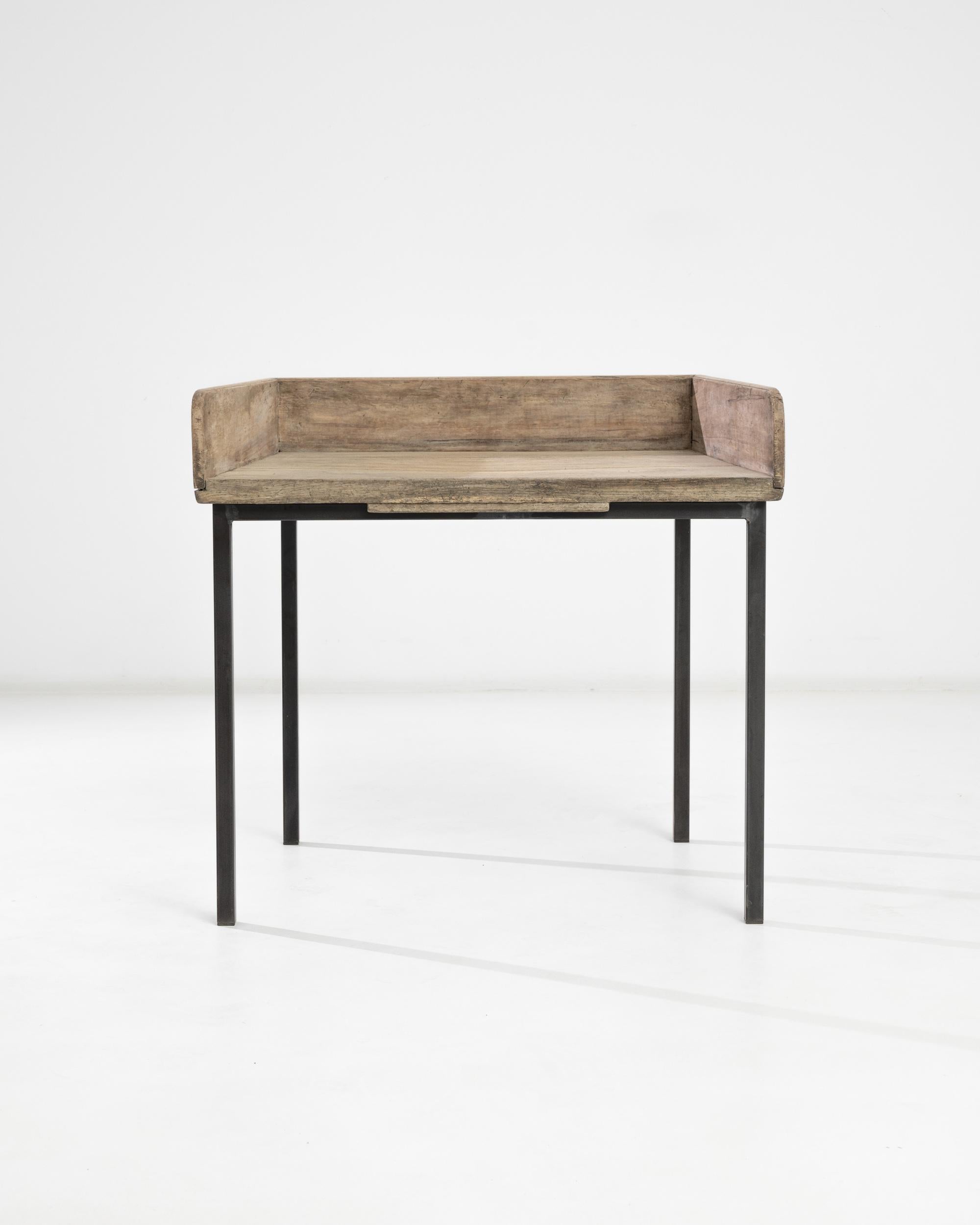 A 20th century wooden side table with a metal frame, from Central Europe. With a charmingly rustic wooden top perched on slim metal legs, this side table presents a versatile profile. Originally contrasting, the minimalist metal design and soft