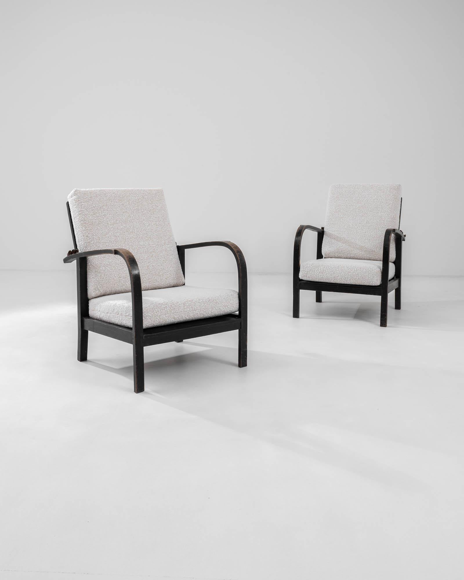 A pair of wooden upholstered armchairs created in 20th century central Europe. Characteristic of mid-century central European design, these chairs exude a forthright and functional demeanor that nonetheless is brimming with aesthetic charm. A simple