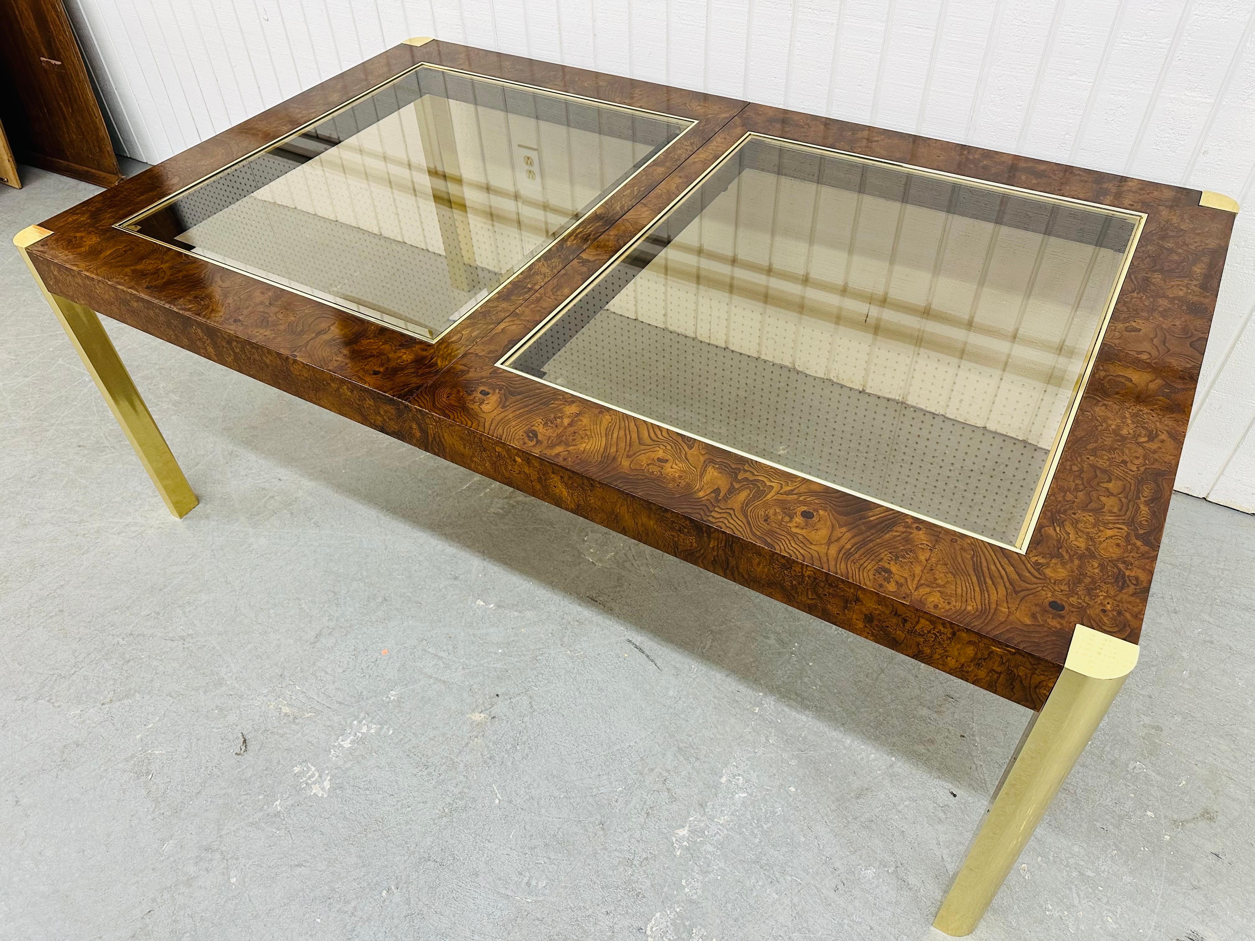 This listing is for a Vintage Century Furniture Burled Walnut Dining Table. Featuring a straight line design, the top is a combination of burled wood and glass inserts, four removable brass legs for easy transport, and two large leaves that extend
