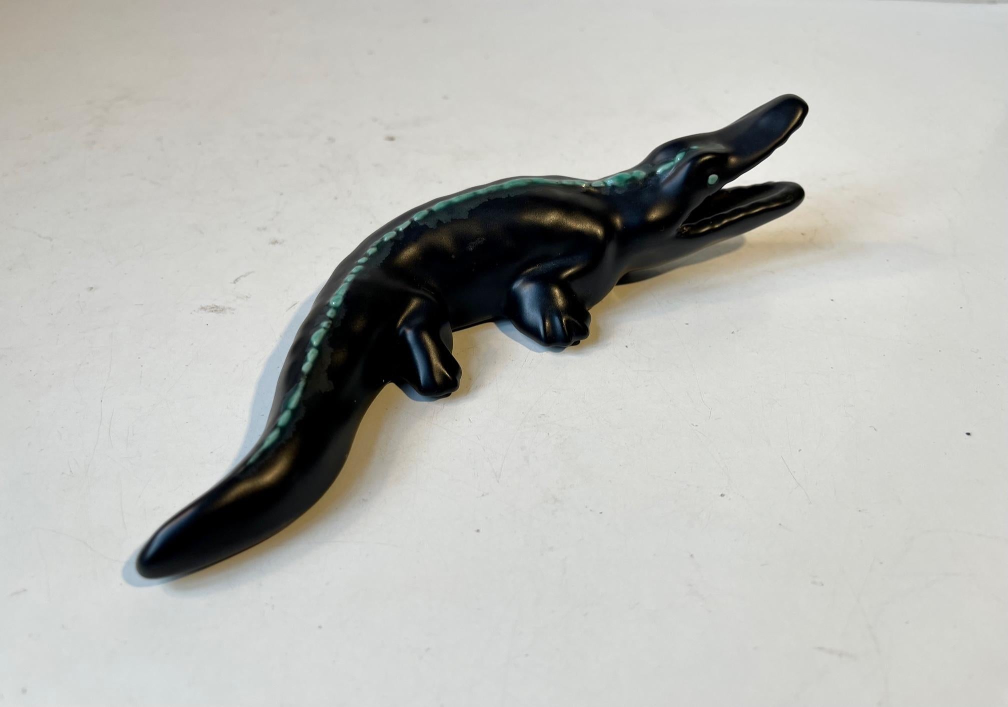 A glazed black crocodile or Alligator decorated with green dots across its spine. It can be displayed lying of wall mounted. Designed and made at Søholm in Denmark circa 1950-60. Measurements: L: 20 cm, H: 5 cm, W: 7.5 cm.