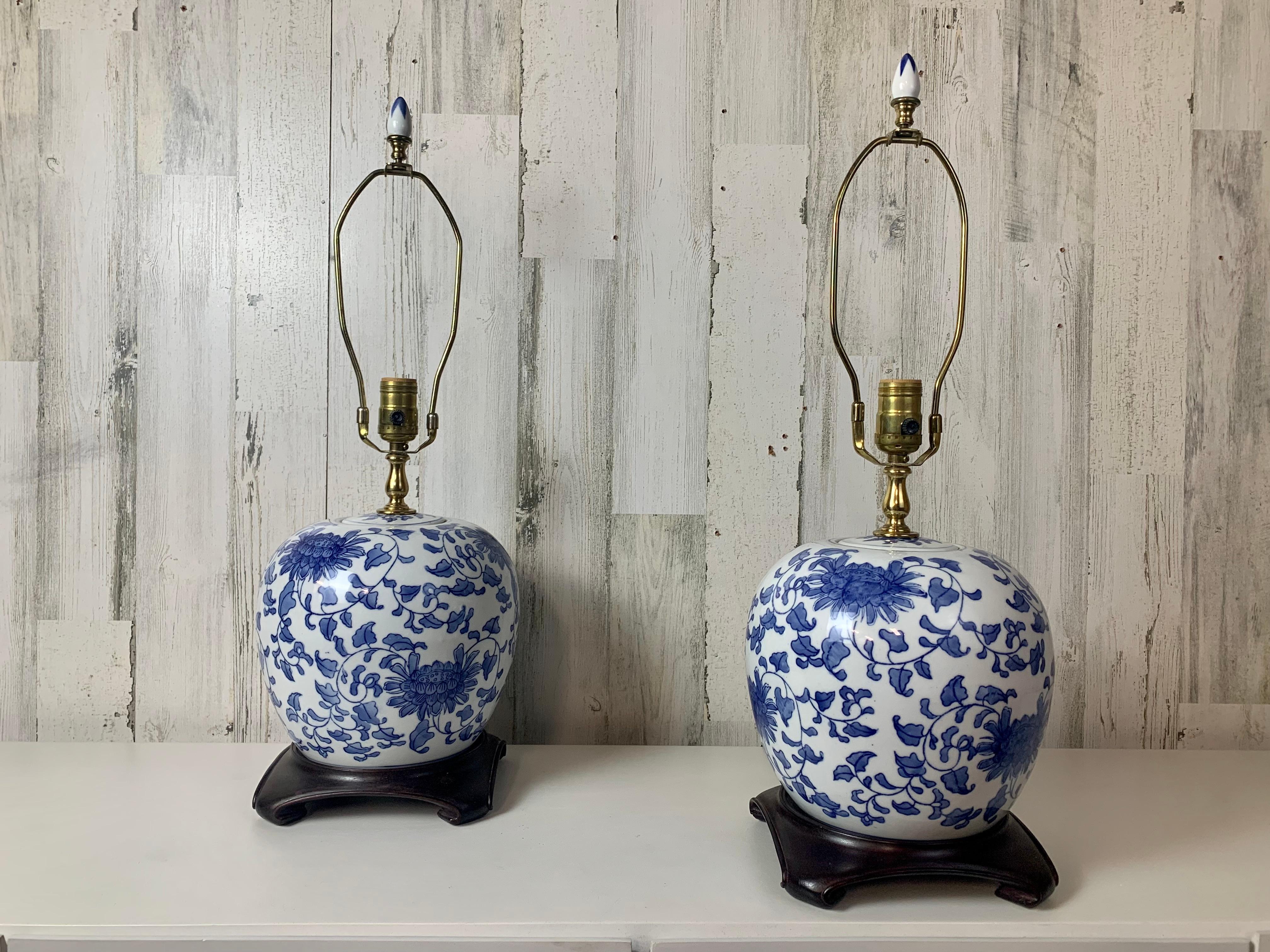 Beautiful Blue and white hand painted ceramic ginger jar lamps made in Hong Kong in the 1980s. mounted in mahogany scroll bases with original ceramic finials.