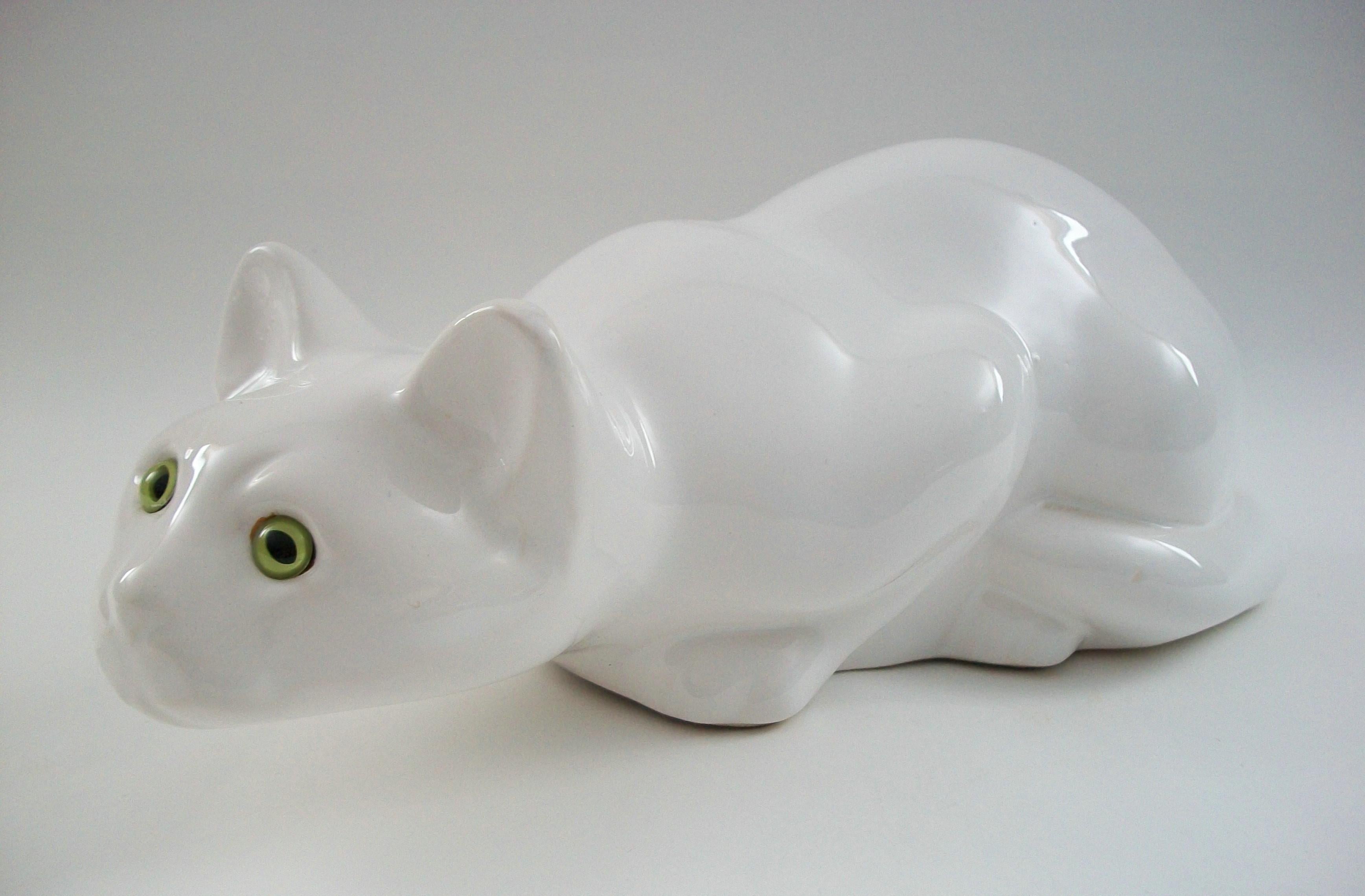 Vintage ceramic cat with green glass eyes - life size model - featuring an over-all white glaze - glazed interior - unsigned - Italy - circa 1980's.

Excellent vintage condition - minor glaze chip to one ear - glaze stress crack (as photographed) -