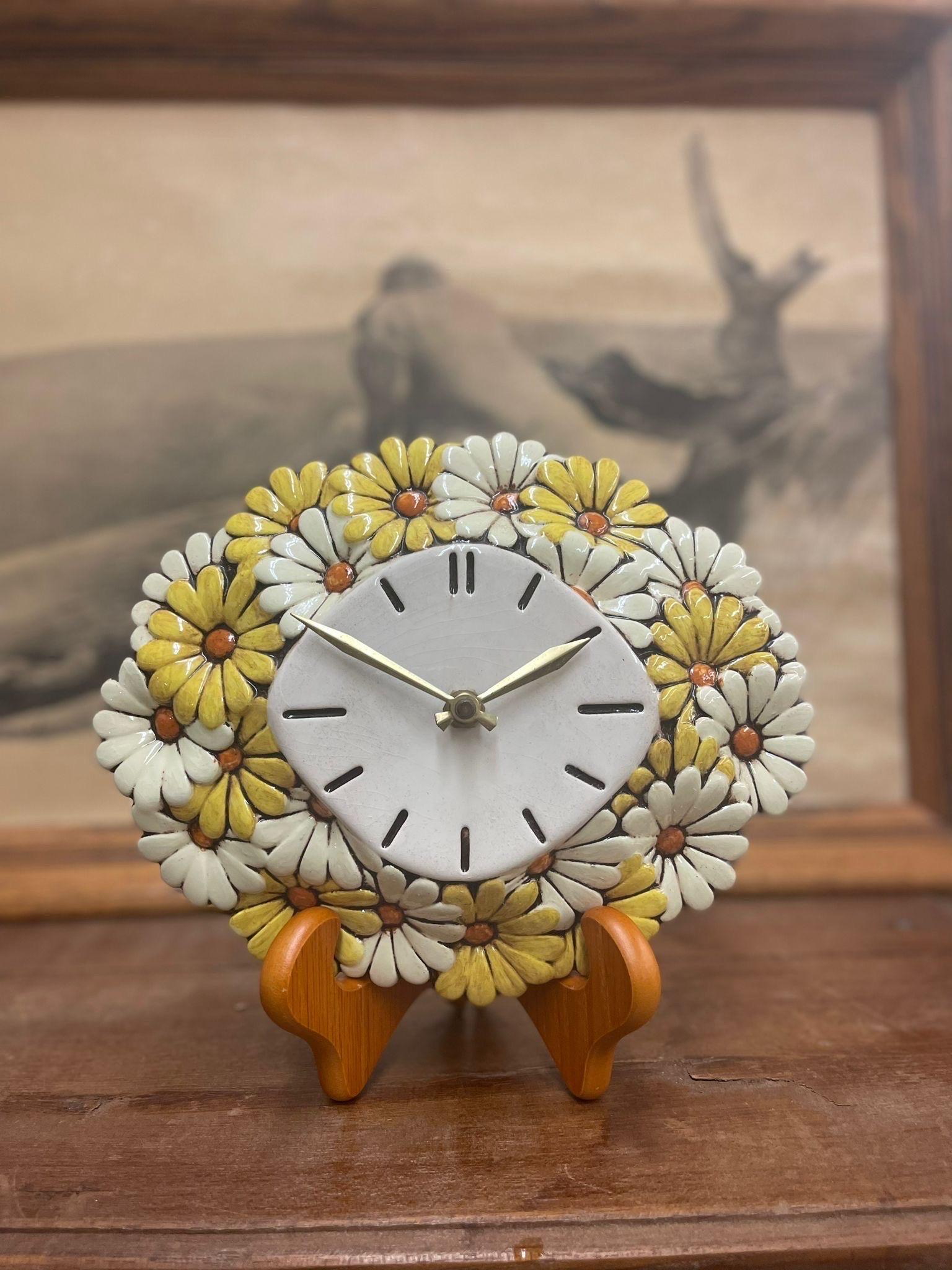 Wall Clock with Daisy Border. Stand Not Included. Operational Ability Unknown. Makers Mark on the back.

Dimensions. 10 W ; 3 D ; 8 H