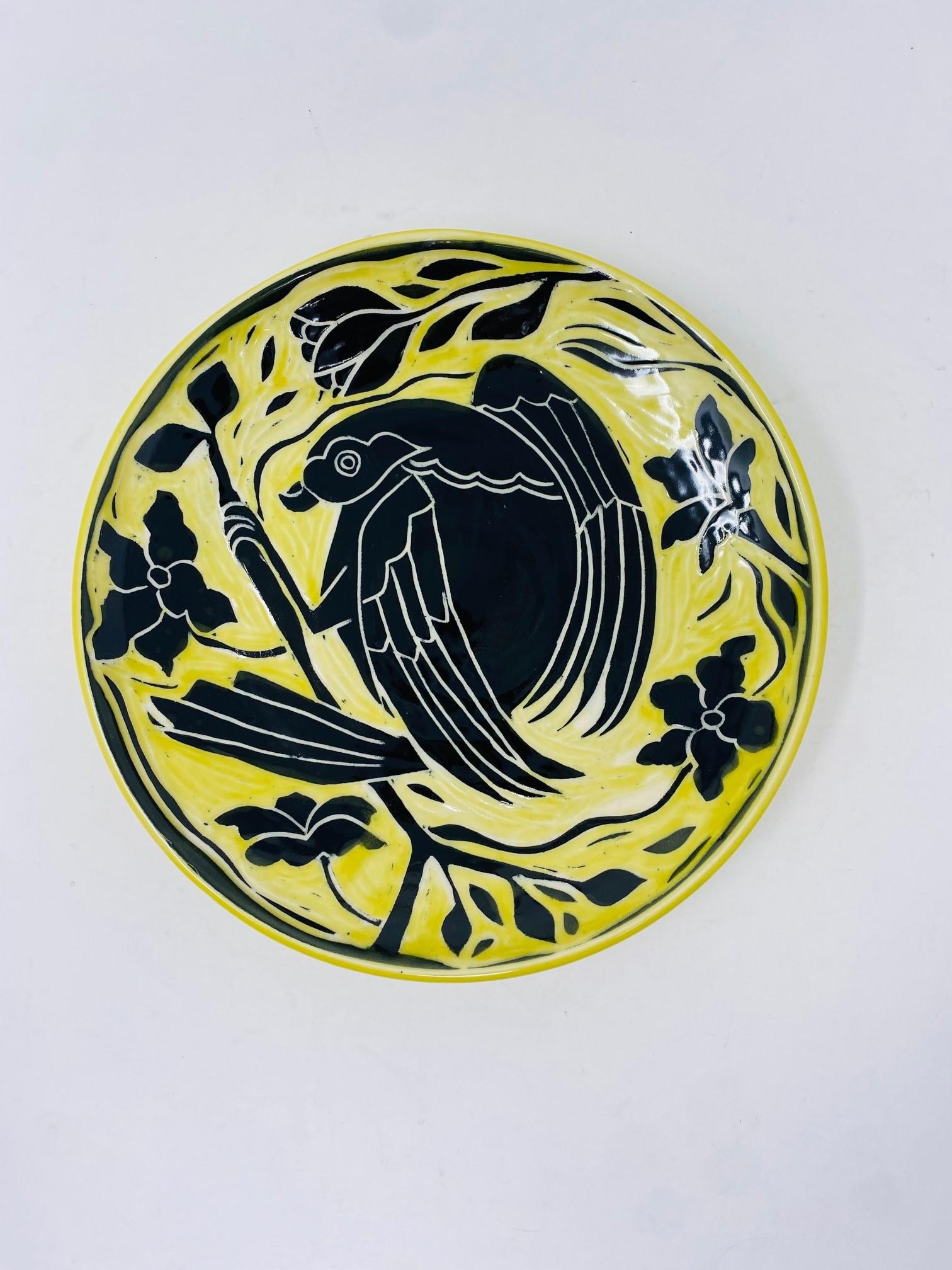 Beautiful ceramic plate with design.  This piece is joyful, eccentric and classic at the same time.  The ceramic is finished with a beautiful yellow glaze that envelops a bird figure on a branch.  The classic depiction combined with the yellow hues