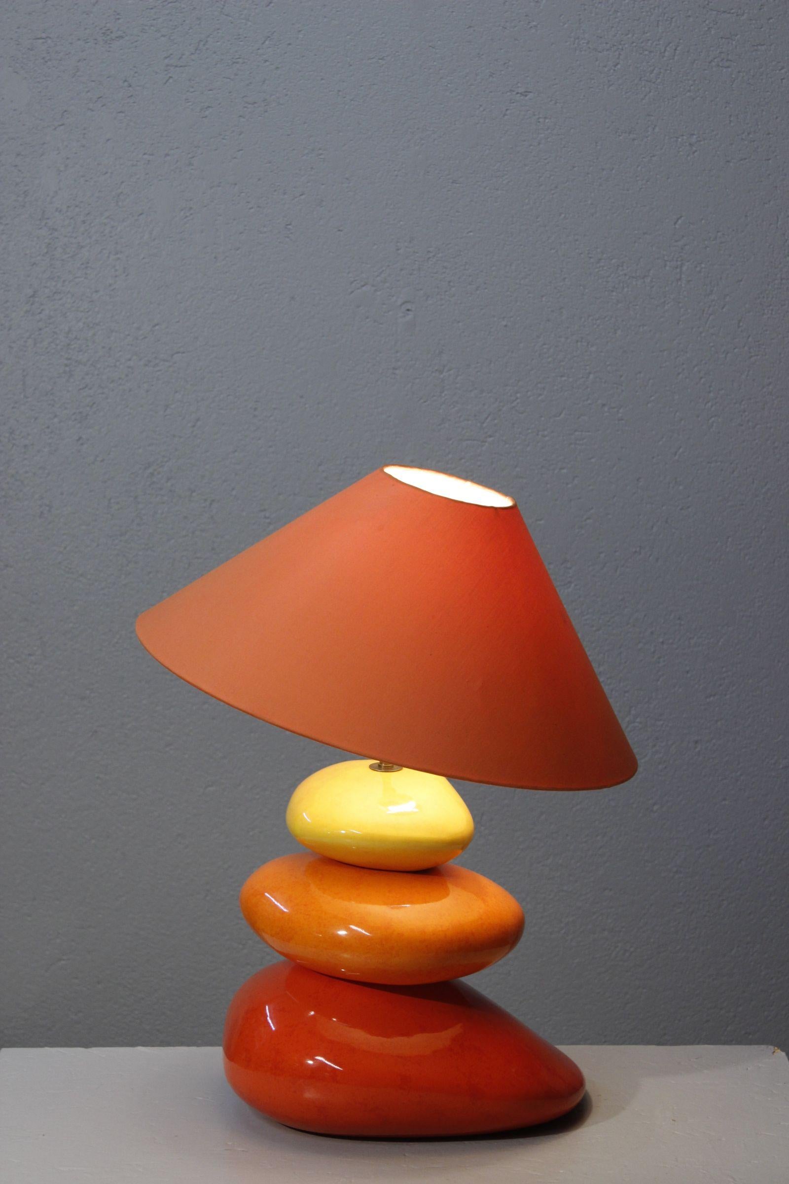 Large pebble lamp by François Chatain, France circa 1990. 

Composed of three glazed ceramic pebbles alternating between red, orange and yellow, surmounted by a brass rod housing the socket on a brass pivot allowing orientation of the shade.