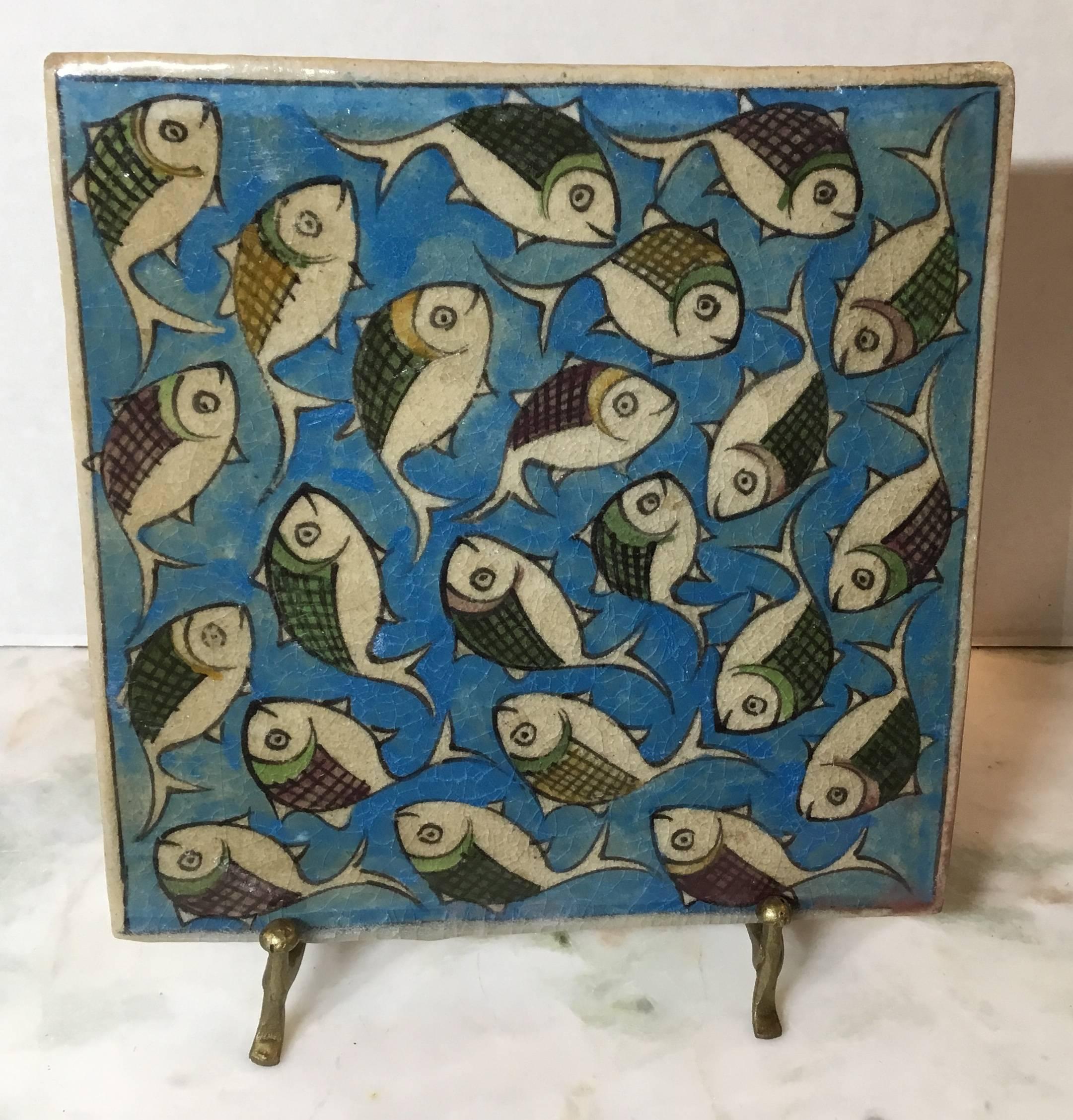 Beautiful Persian tile hand-painted and glazed with exceptional wondering school of colorful fish on a turquoise color background.
The tile can hang on the wall, or display on custom made iron stand.
Display piece included.
