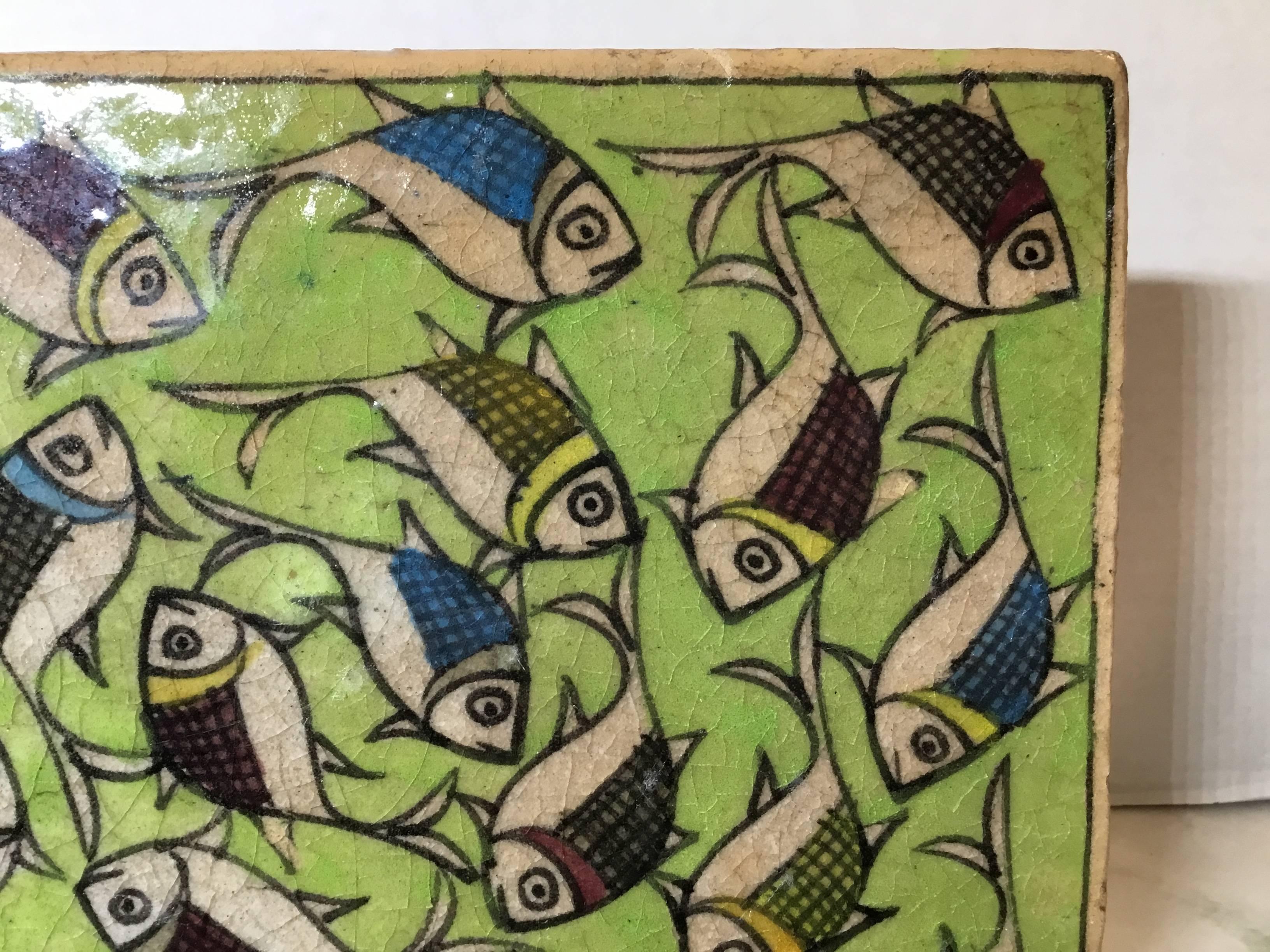 Beautiful Persian tile hand painted and glazed, with exceptional colorful wondering school of fish on a green color background.
You can hang the tile on the wall or display it on a custom made iron display piece. Display piece included.