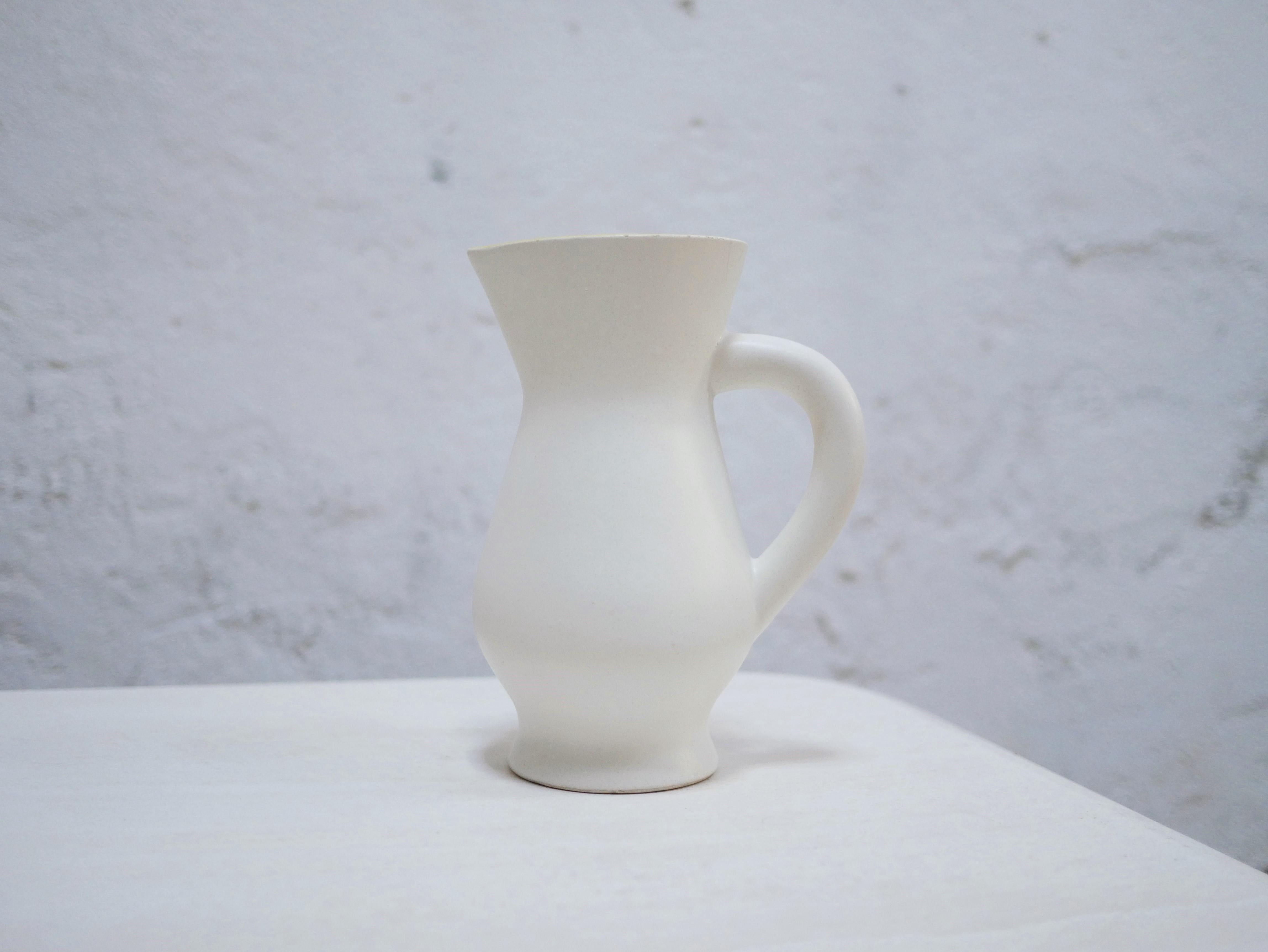 Ceramic pitcher designed by the Saint Clément factory in the 1950s.

Trendy and current, this pitcher does not lack character and elegance. Nice contrast between the minimalist milky white exterior and the vibrant yellow interior.
It will be perfect