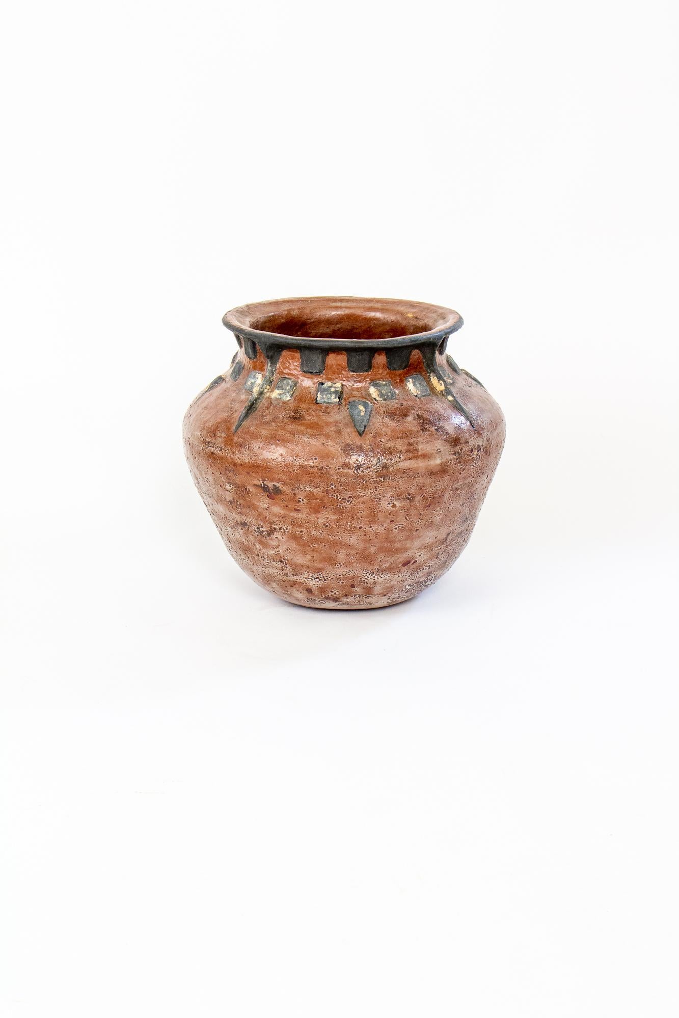 Large ceramic pot, perfect for interior plants. Made of a light colored ceramic, with black and red-brown glaze to resemble earthenware. Rustic design with triangles and squares, and a rough finish. Signed, “WMG”.