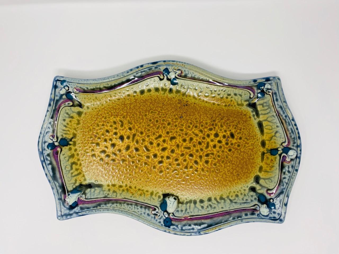 Beautifully created and in excellent condition vintage ceramic platter. The finish on this platter evokes an optic illusion of reptile skin in the center as it is beautifully framed by hues of blue, purple and beige glaze. This piece is 15.5” wide