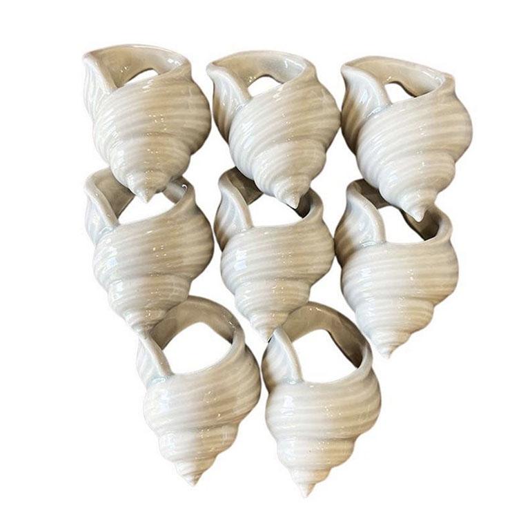 Ein Satz von 8 Serviettenringen aus Keramik mit Muscheln in hellem Grau. Dieses Set ist eine fabelhafte Ergänzung für eine küstennahe Tischdekoration. Jedes Stück ist in einem hellen, blassen Grau glasiert. Verwenden Sie dieses Set zusammen mit