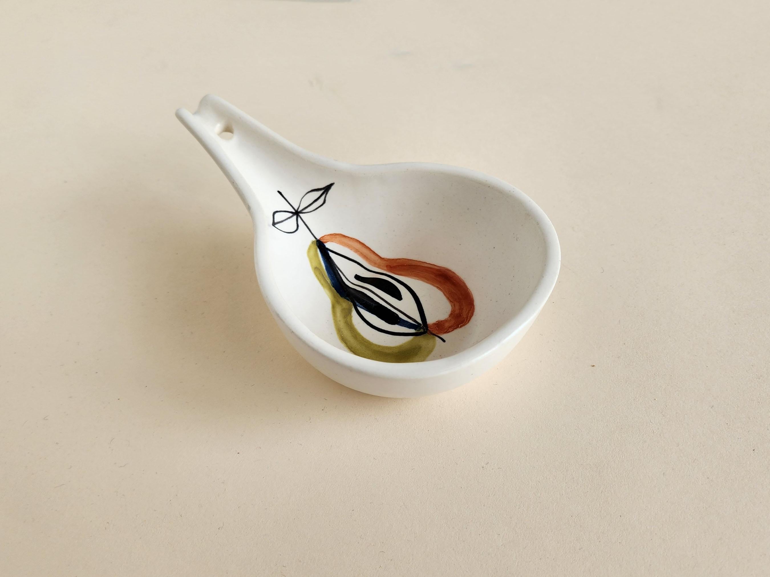 Vintage ceramic spoon rest signed by Roger Capron - Vallauris, France

Roger Capron was in influential French ceramicist, known for his tiled tables and his use of recurring motifs such as stylized branches and geometrical suns.   He was born in