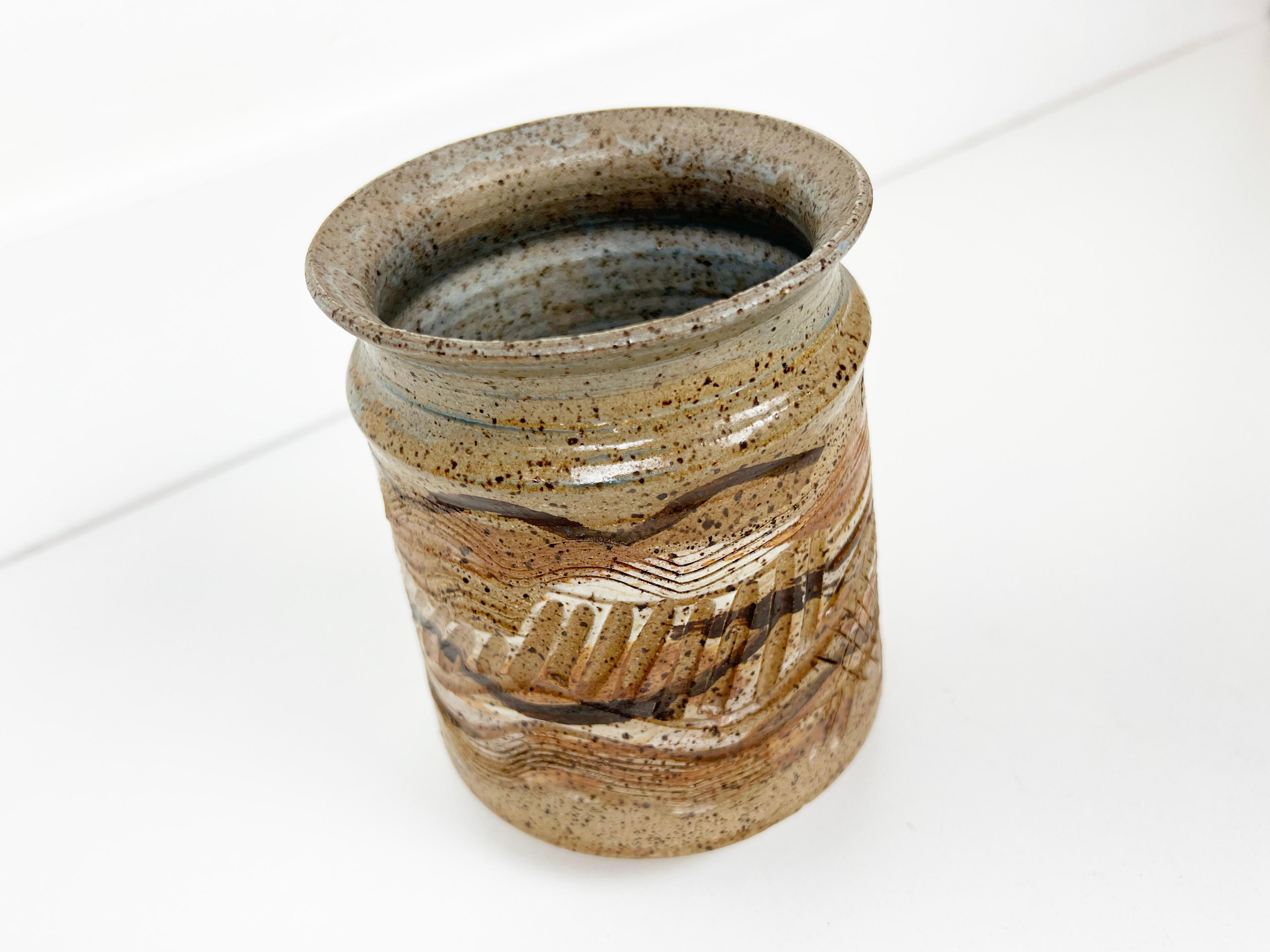 Vintage ceramic vase or planter glazed in browns, whites and orange with a variety of tool markings creating texture and depth. Signed.

Year: 1970s

Style: Mid-Century Modern

Dimensions: 5.5