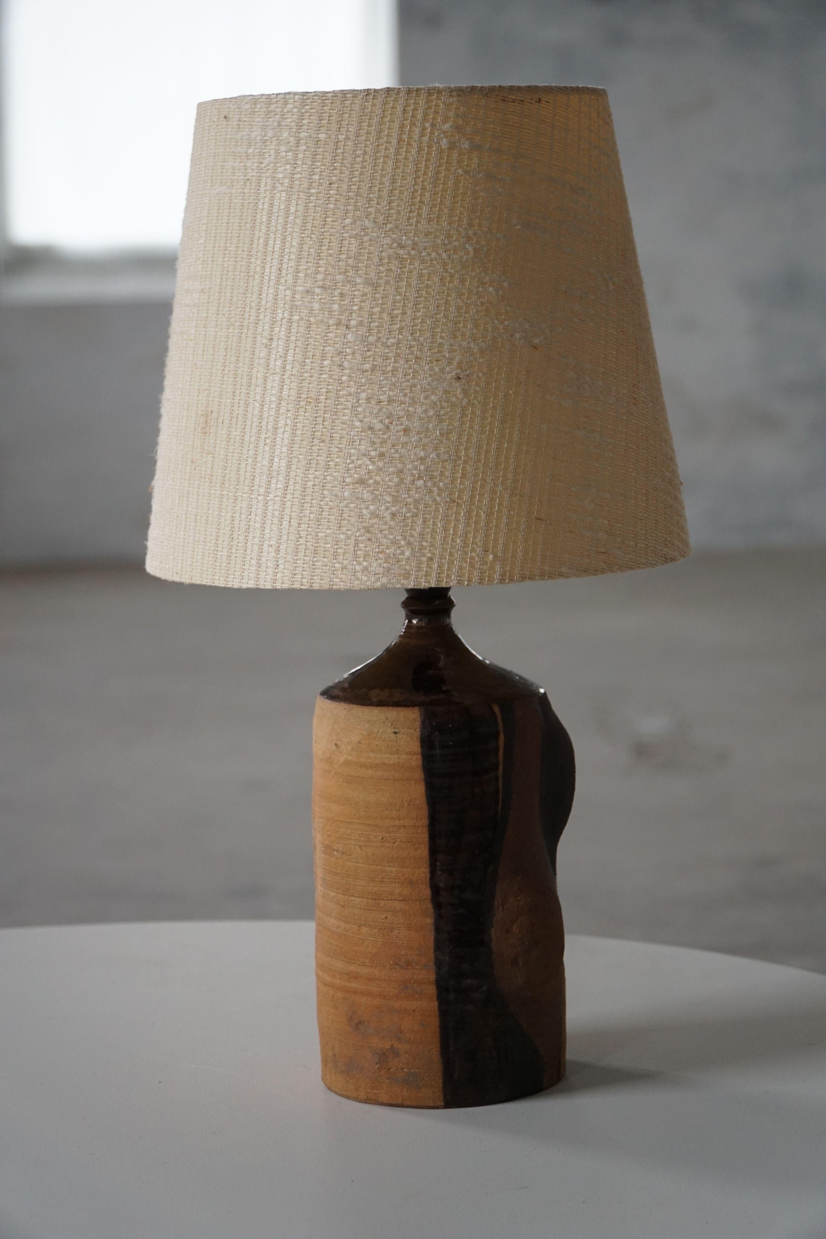Questa sorprendente lampada da tavolo vintage è stata realizzata in Danimarca negli anni '50 e presenta un audace disegno geometrico dipinto a mano in toni ricchi e terrosi. Le sfumature del marrone caldo, del giallo oro e dell'ocra creano una