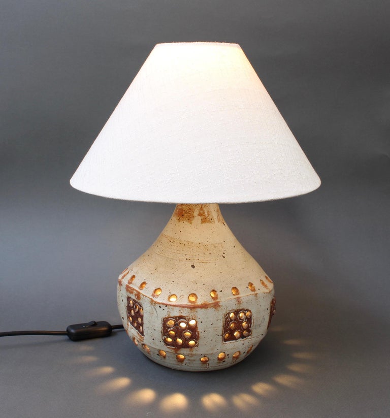 Ceramic table lamp in the style of Georges Pelletier (circa 1970s). An oatmeal-coloured base glaze forms the background for this delightful arabesque ceramic piece. Terracotta coloured patches add visual interest. The piece is perforated with