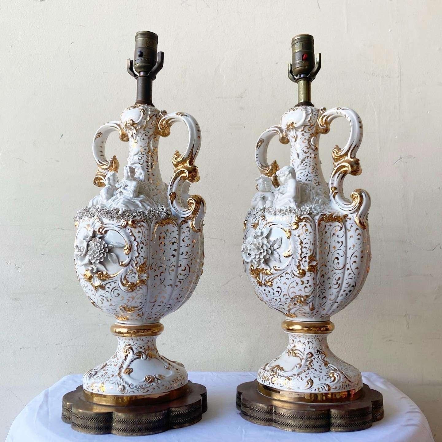 Incroyable paire de lampes de table vintage ornées. Chaque lampe présente un design complexe de fleurs et d'angelots en blanc et or.

