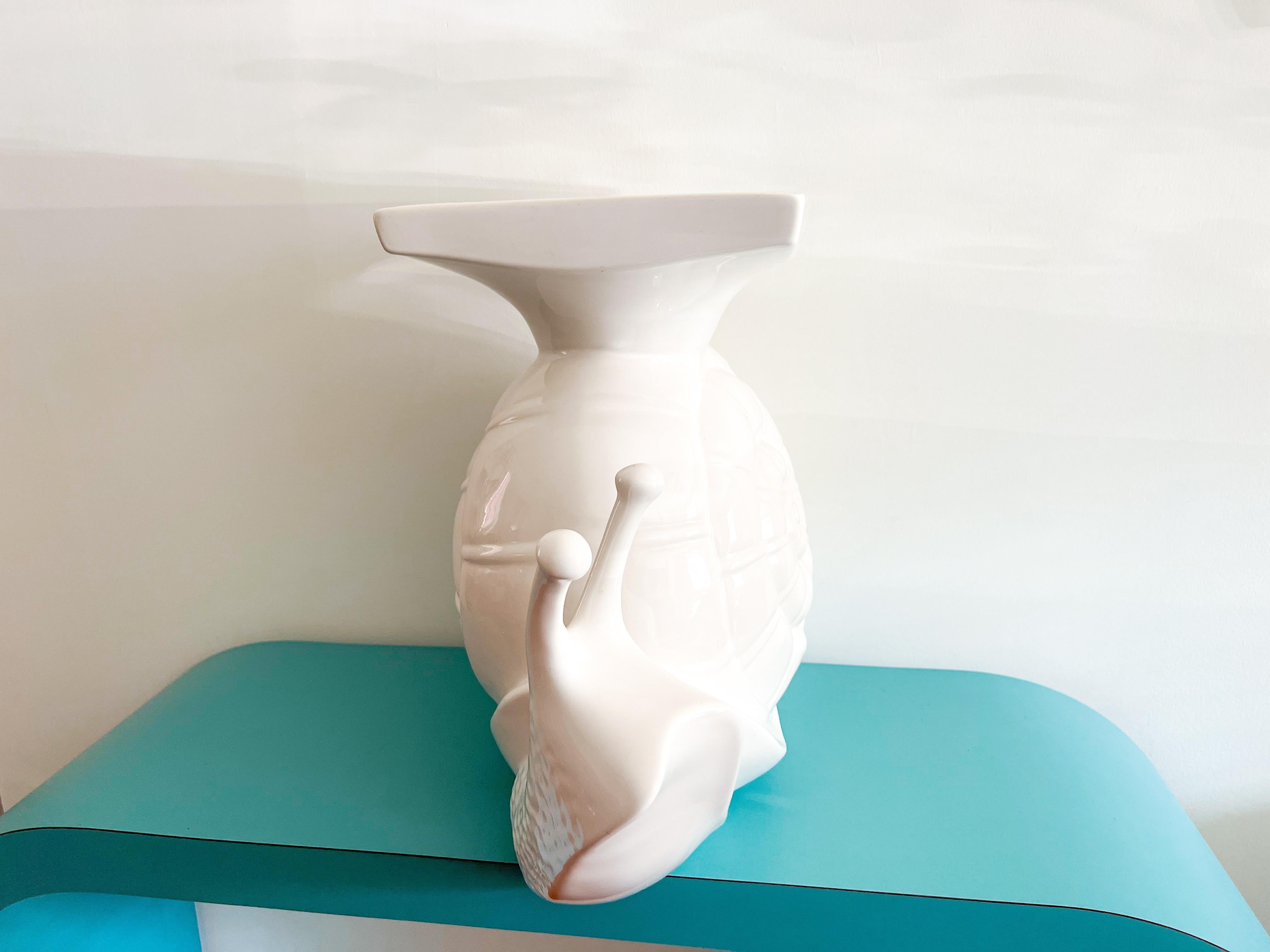 A distinctive garden table/stand made of white glazed ceramic, featuring a unique and exceptional snail design. 
This item is an ideal addition for those seeking a statement piece. It boasts remarkable sturdiness and can accommodate large plants