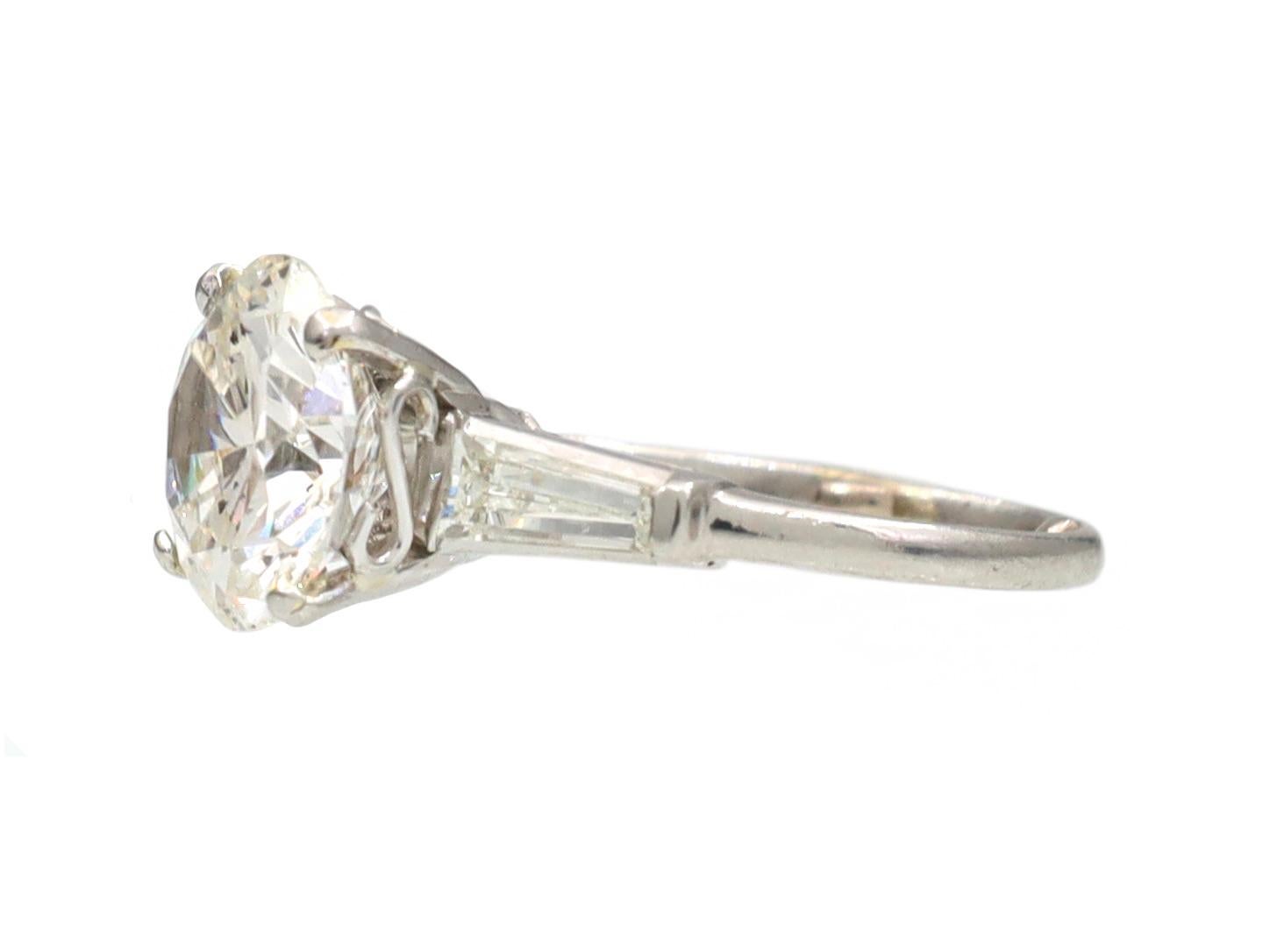 Vintage 3.00ct diamond flanked solitaire engagement ring in platinum. Centred with an estimated 3.00ct round brilliant cut diamond, G colour, SI1 clarity in a four claw setting, flanked to either side with two tapering baguette cut diamonds in
