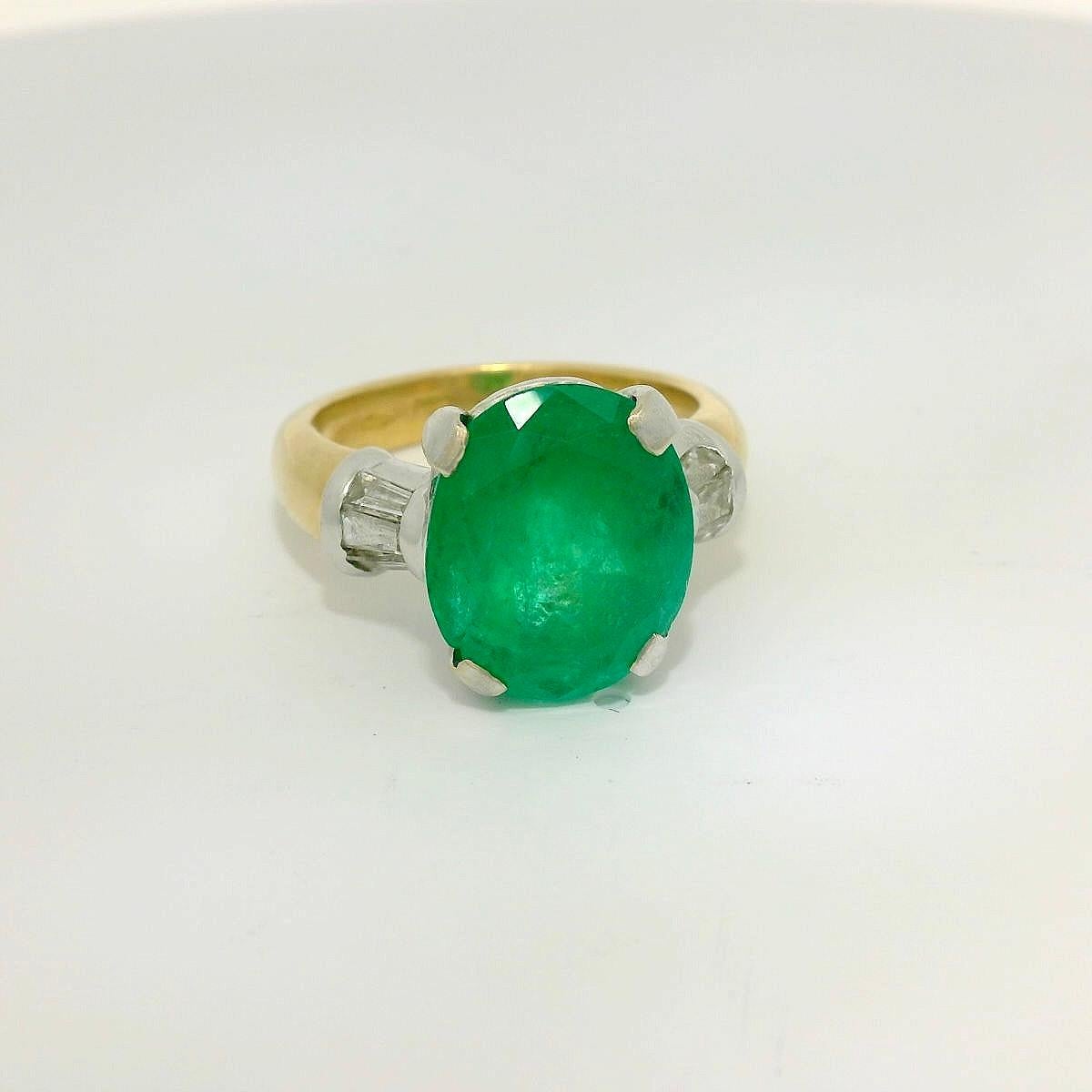 Vintage Emerald and diamond ring. 

Bicolore White and yellow gold 18 Karat ring set with a center oval shape Emerald of approximately 7.15 Carats (Certified Gemreport, a well-known Laboratory in Antwerp, Belgium) and 6 taper shape diamonds for a