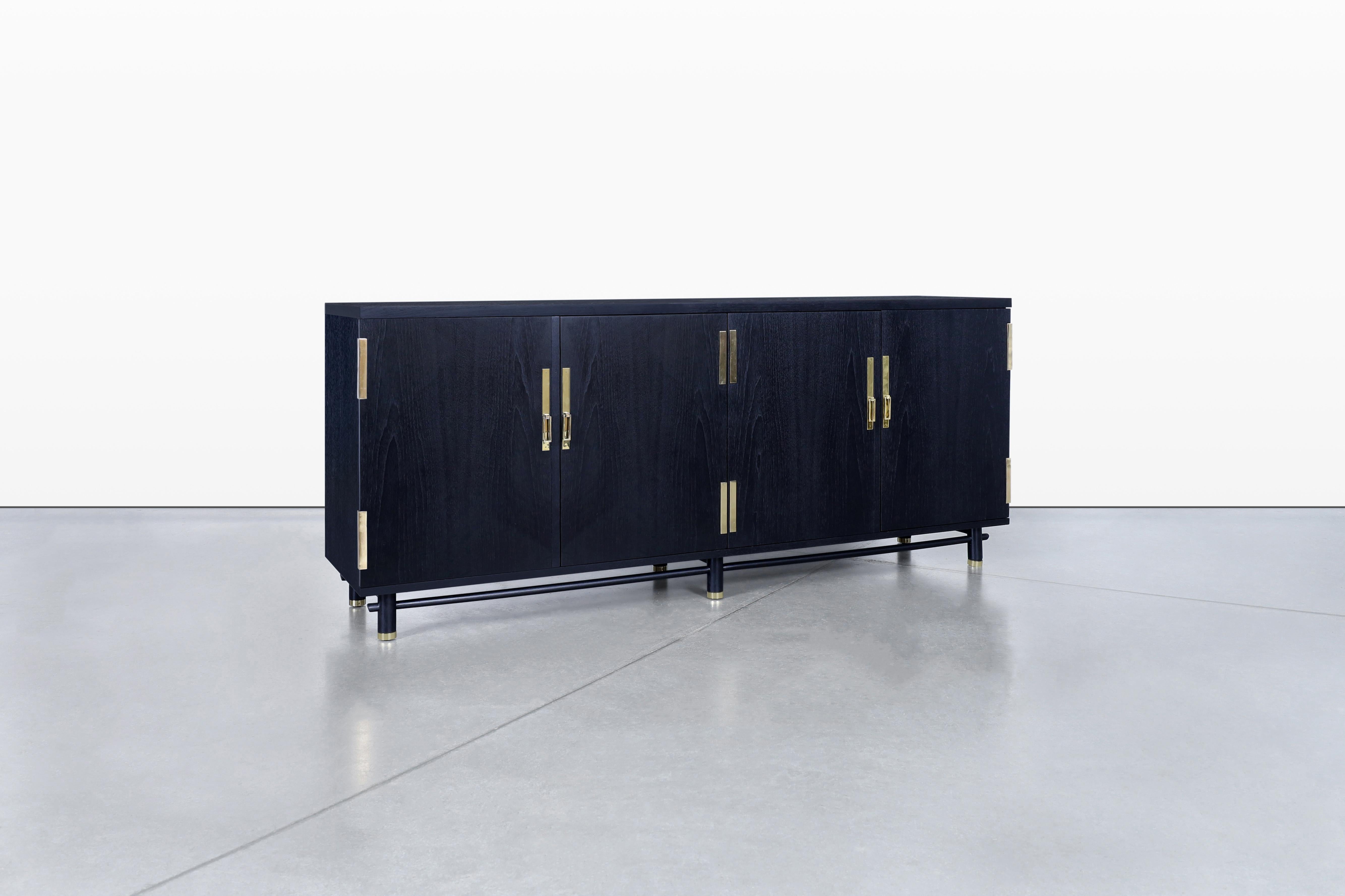 Discover a stunning vintage credenza designed by Michael Taylor for Baker Furniture in the 1960s, showcasing exquisite craftsmanship and timeless style. This remarkable piece features four elegantly designed doors, adorned with original solid brass
