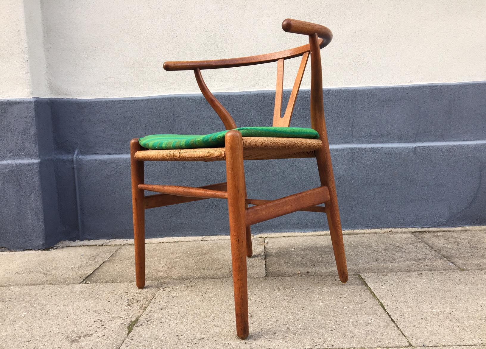 The CH24, Wishbone or Y-Chair was designed by Danish architect Hans Jørgen Wegner in 1949. This model was fashioned out of oak and manufactured by Carl Hansen & Søn in Denmark during the 1960s. The green period seat-cushion is included. The chair