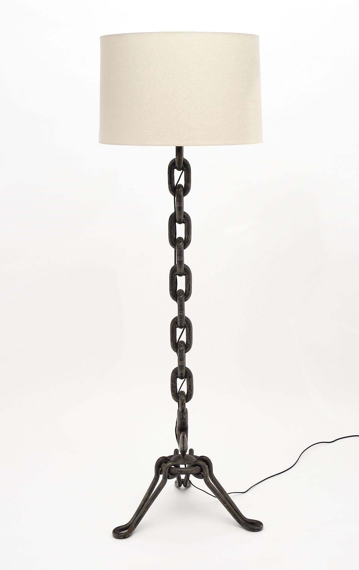 Floor lamp in the French Industrial style made of cast iron featuring a line of chain links with a hook above the tripod base. This piece has been newly wired to US standards.