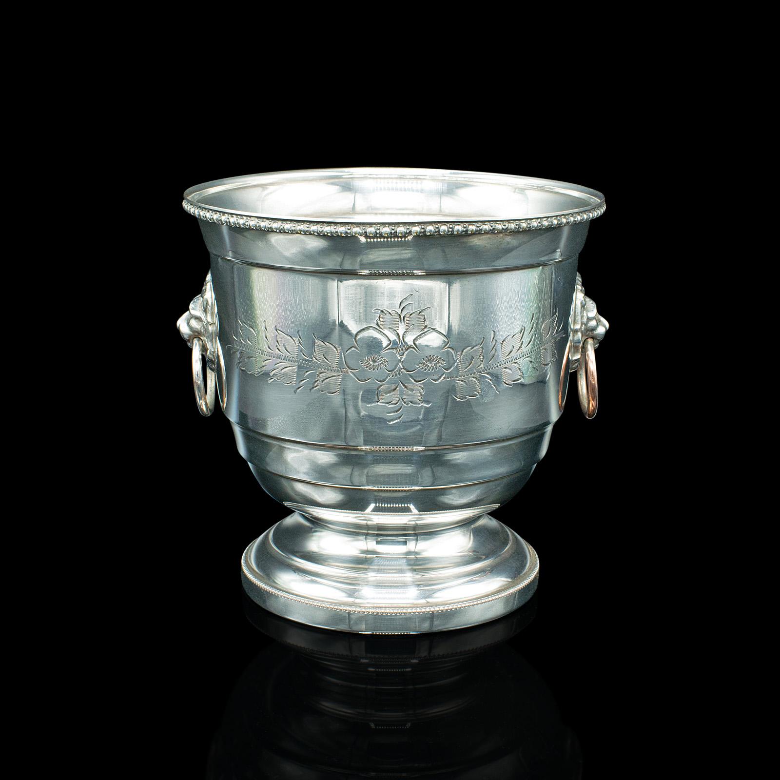 This is a vintage champagne bottle cooler. An English, silver plate ice bucket, dating to the mid 20th century, circa 1950.

Appealing bottle cooler with hand-engraved detail
Displays a desirable aged patina and in good order
Bright silver plate