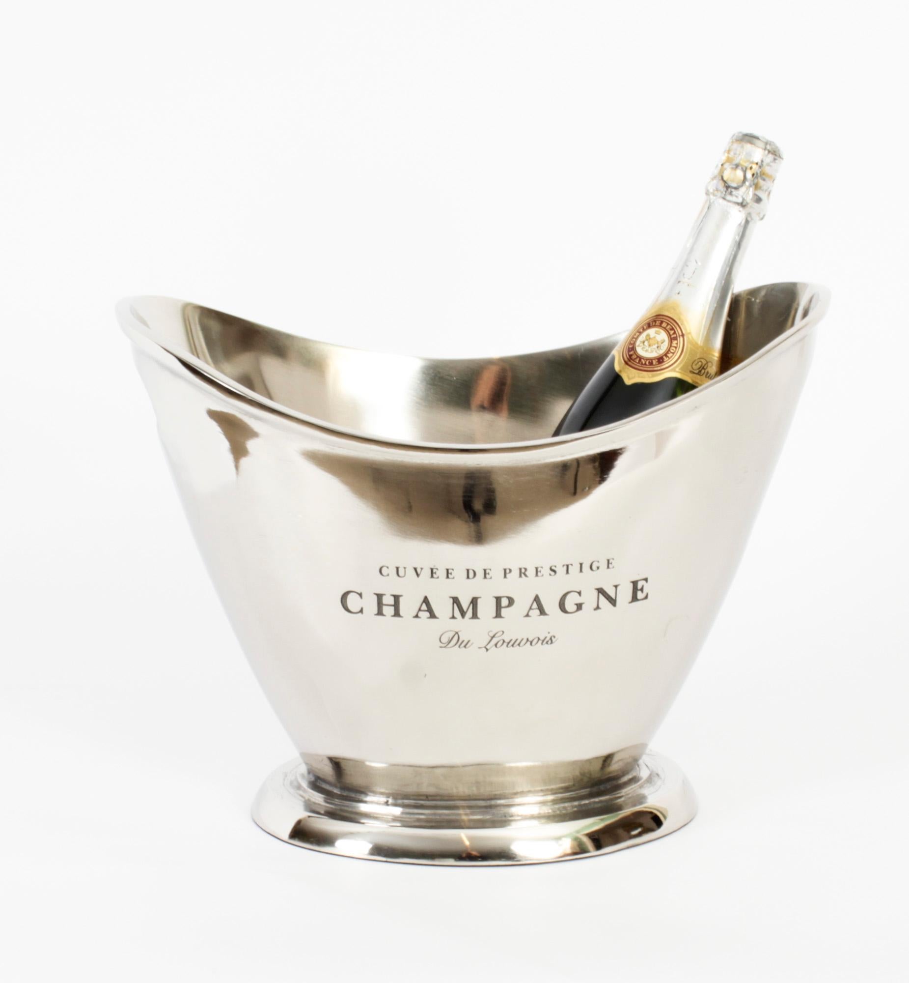 This is a gorgeous vintage nickelplated champagne cooler dating from the late 20th century. 

It is engraved Cuvee De Prestige Champagne Du Louvois boldly on to the side.

The cooler has twin carrying handles and there is no mistaking the unique