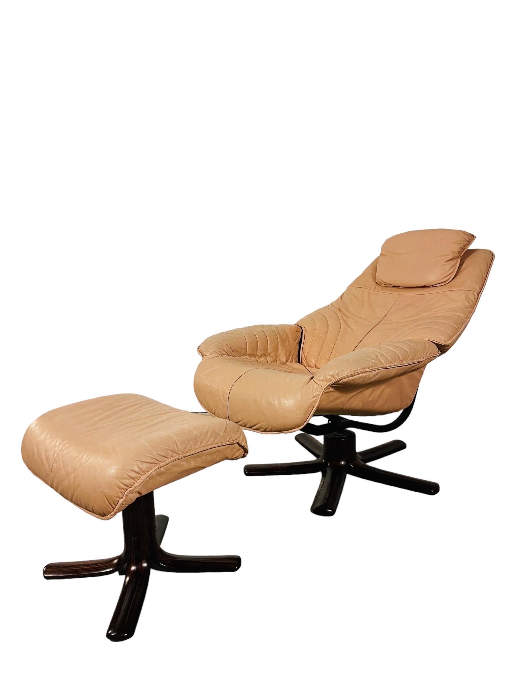 Entrez dans le monde du design norvégien classique avec cette chaise longue en cuir Hjellegjerde vintage et son ottoman. Fabriqué en Norvège, cet ensemble incarne le luxe et le confort. Le revêtement en cuir champagne souple témoigne de la qualité,