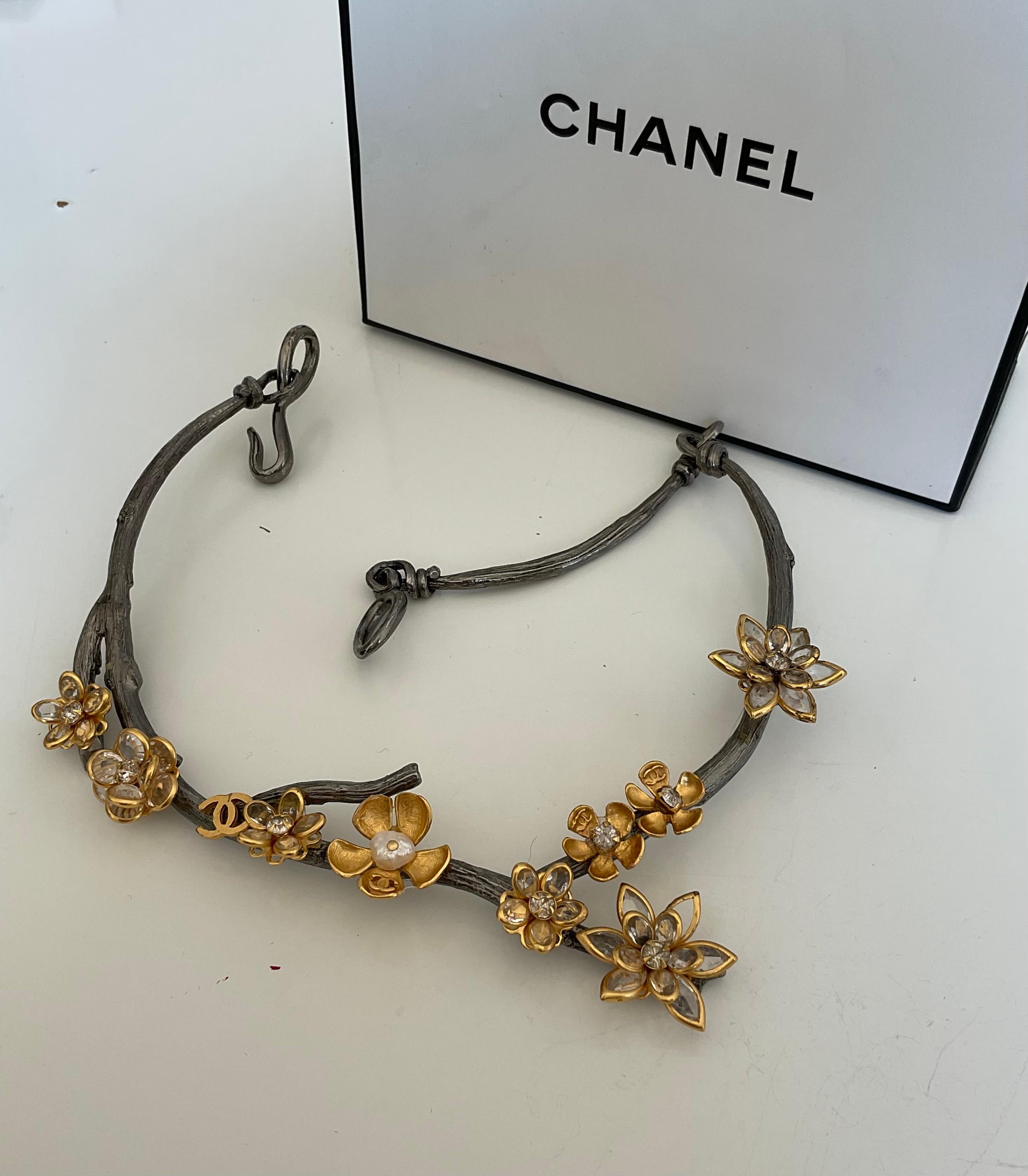 This one-of-a-kind and rare piece is a vintage CHANEL necklace. Designed with gold and silver metals, you will find all along the neckline small to flowers composed of gold and crystals and pearls for the petals and the centre of the flowers.