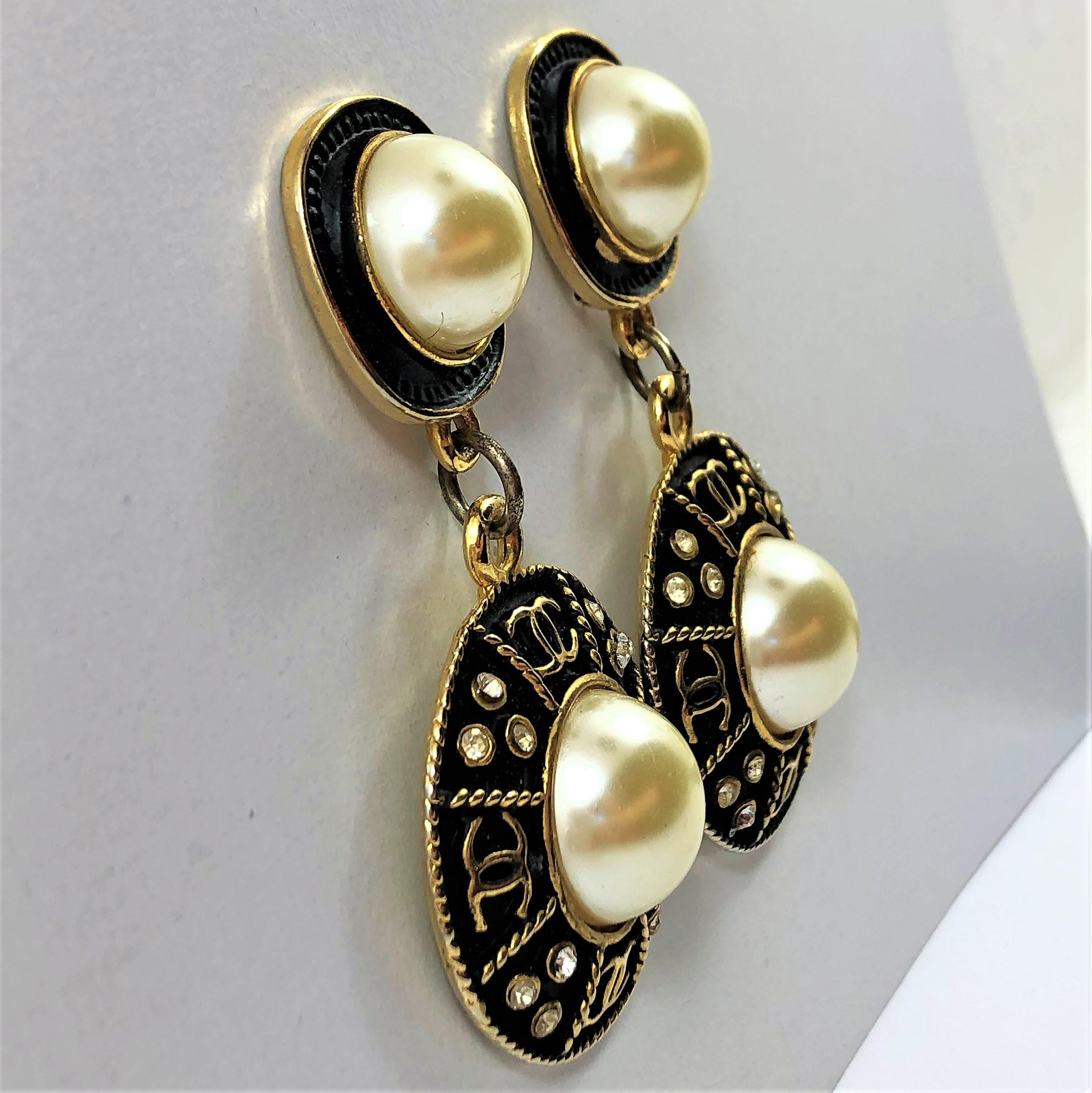 Vintage Chanel  elegant 2 15/16 inch long black finish, faux pearl and rhinestone
earrings. The center pearl is surrounded by four sections spattered with rhinestones
and gold tone CC logo. The bottom part measures 1.5 inches in diameter. Wonderful