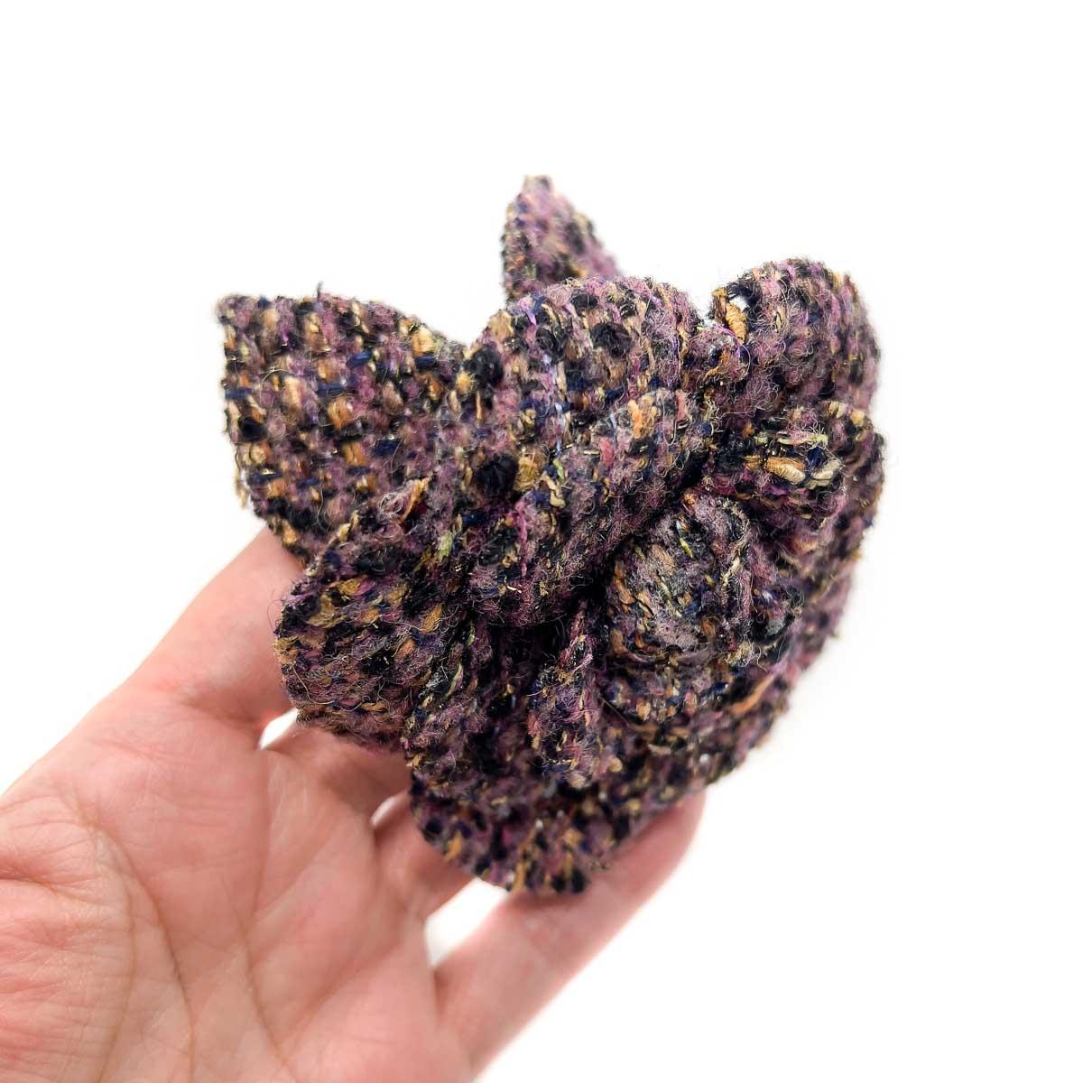 A beautiful rendition of the Vintage Chanel Tweed Camellia Brooch. Crafted in luxurious amethyst, black and gold woven wool to create the tweed. Since the 1920s the camellia has meant more to the House than simply a flower. The Camellia embodies the
